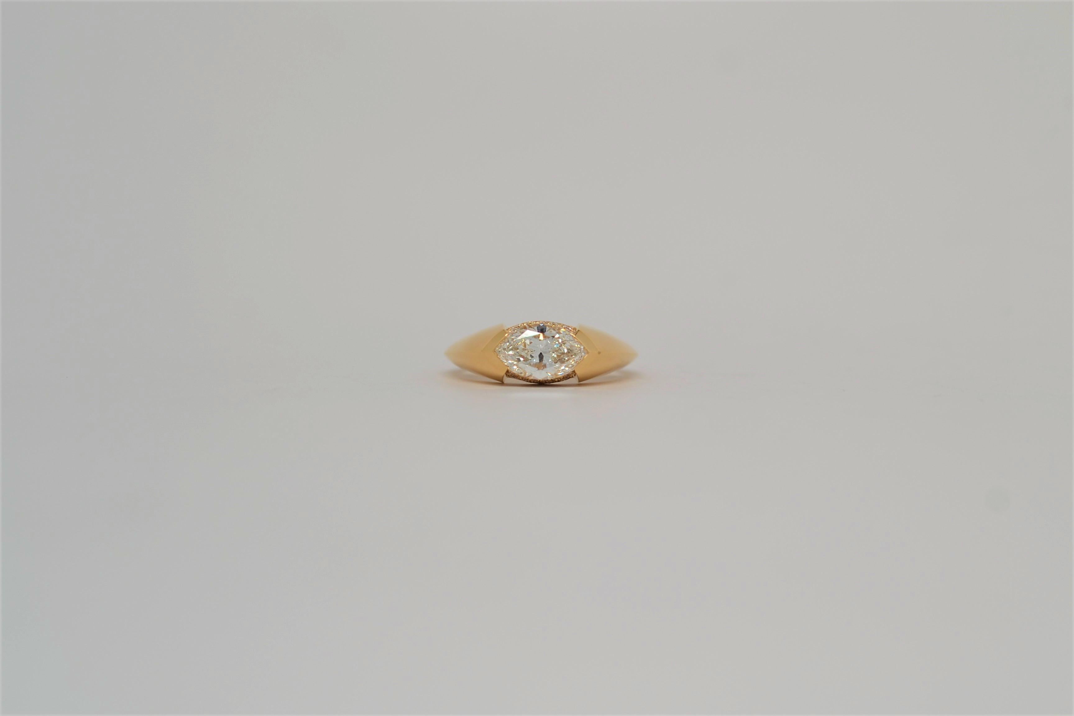This handmade ring is set in 18K Yellow Gold with a Marquise Brilliant Cut Diamond set in an East-West layout. The center diamond is hand set with chevron shaped channels and a knife edge shank. 
Thirty four Round Brilliant Cut Diamonds are bead set