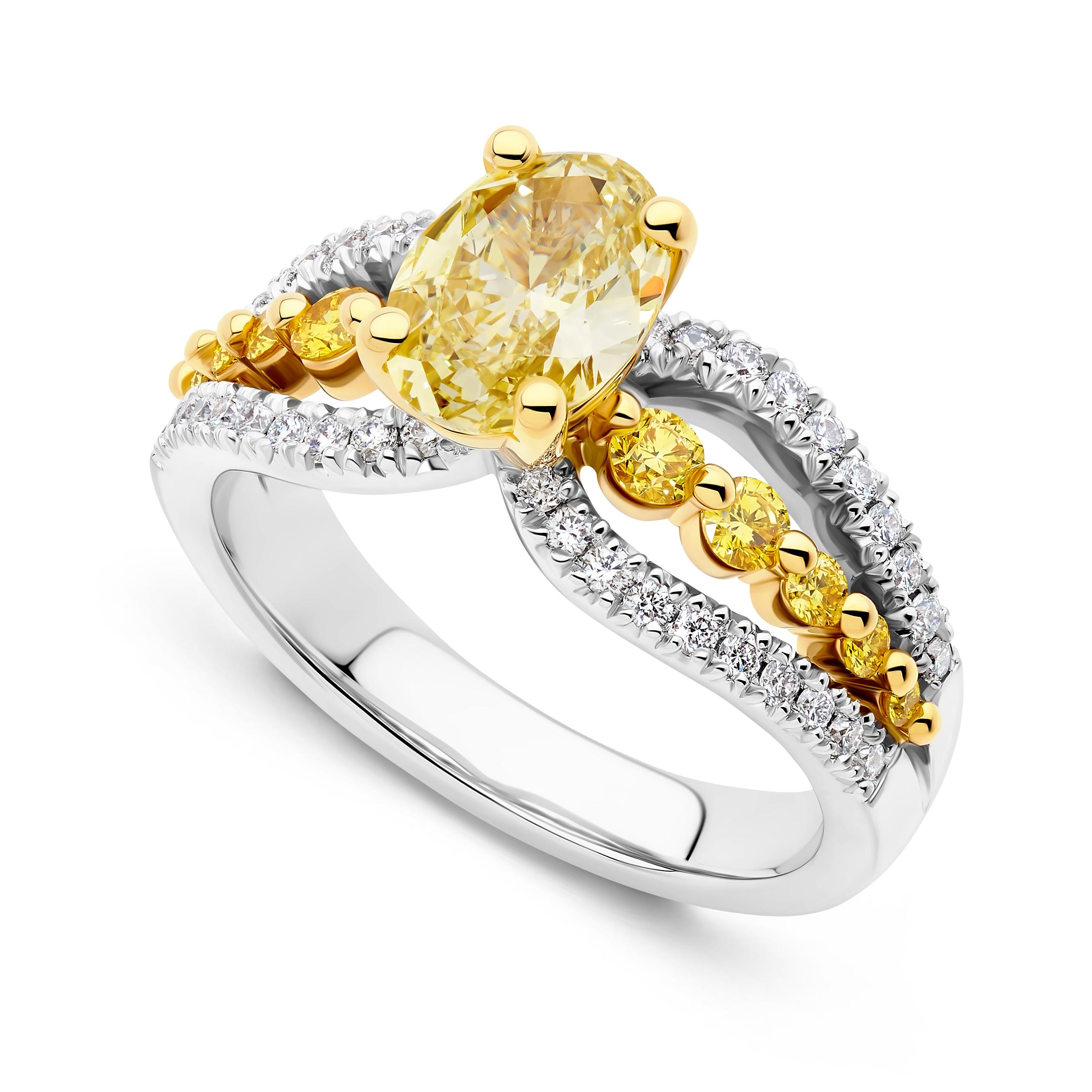 18 karat white gold claw and pave set ring featuring one oval cut GIA certified 1.11cy Fancy Yellow Vs2 clarity diamond and weighing 1.11ct.  Ten round brilliant cut Fancy Vivid / Fancy Intense diamonds of VS clarity totalling 0.305ct.  Thirty round