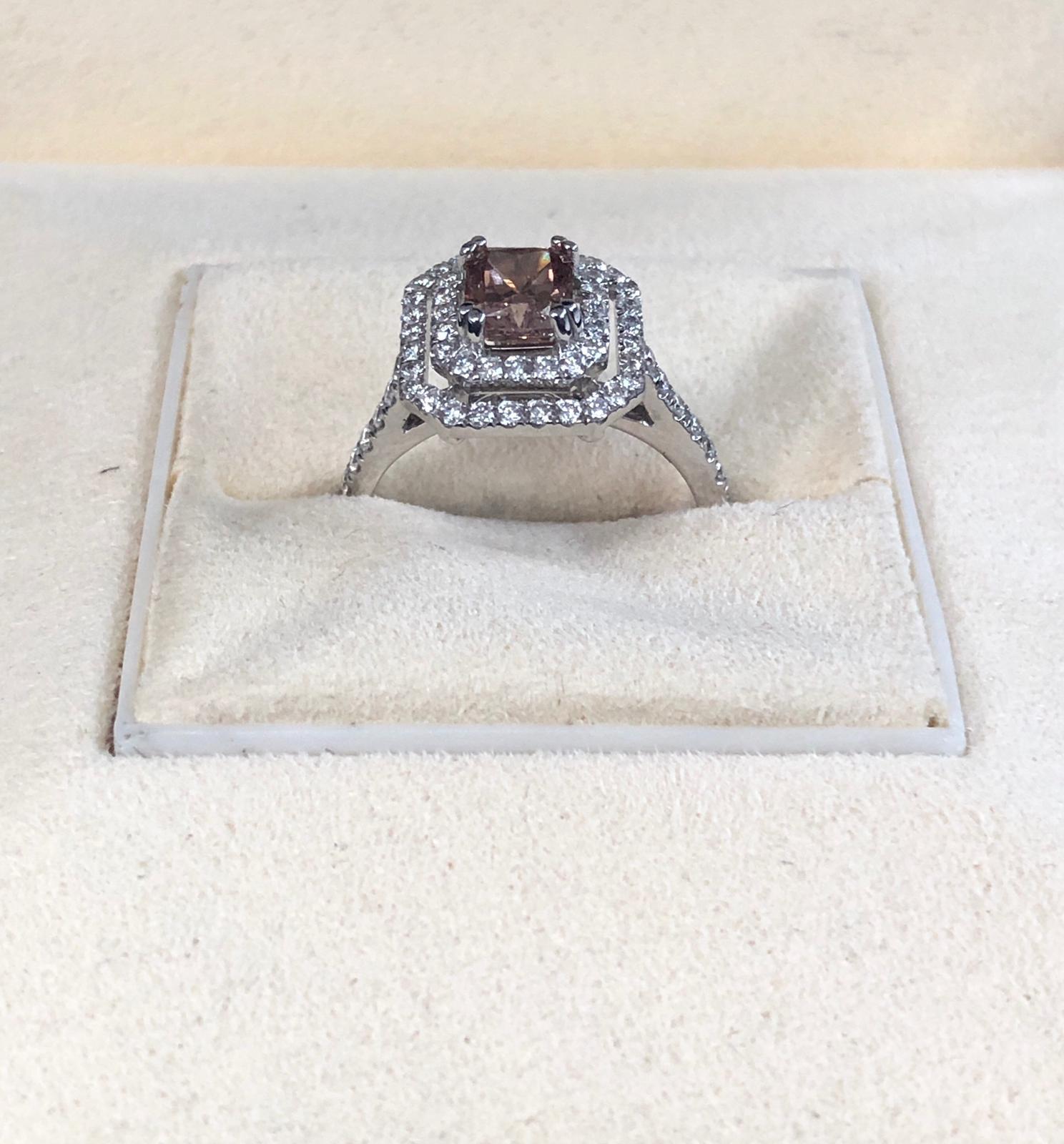 This is a Natural Fancy Pink-Brown Radiant cut diamond weighing 1.12 carats by GIA. surrounded by paved white diamonds in the double halo setting. Its transparency and luster are excellent. set on 18K white gold, this pear ring is the ultimate gift