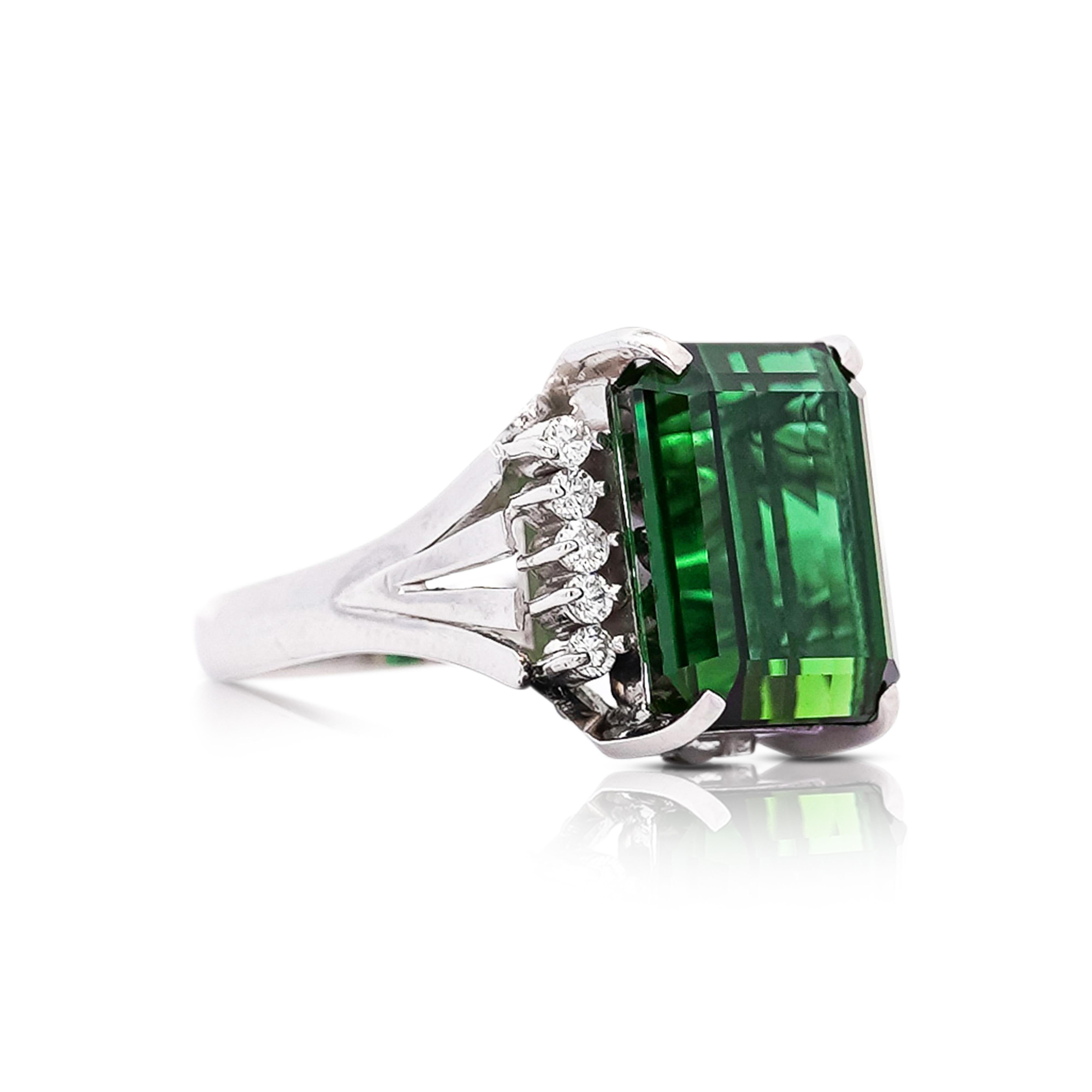 This is a fine piece of jewelry carefully crafted to perfection. This GIA certified 11.22 CT emerald-cut green tourmaline, is set on a platinum 900 band. The 10 0.25 CTTW prong set round-cut diamonds, enhance the gemstones rich green color. Some