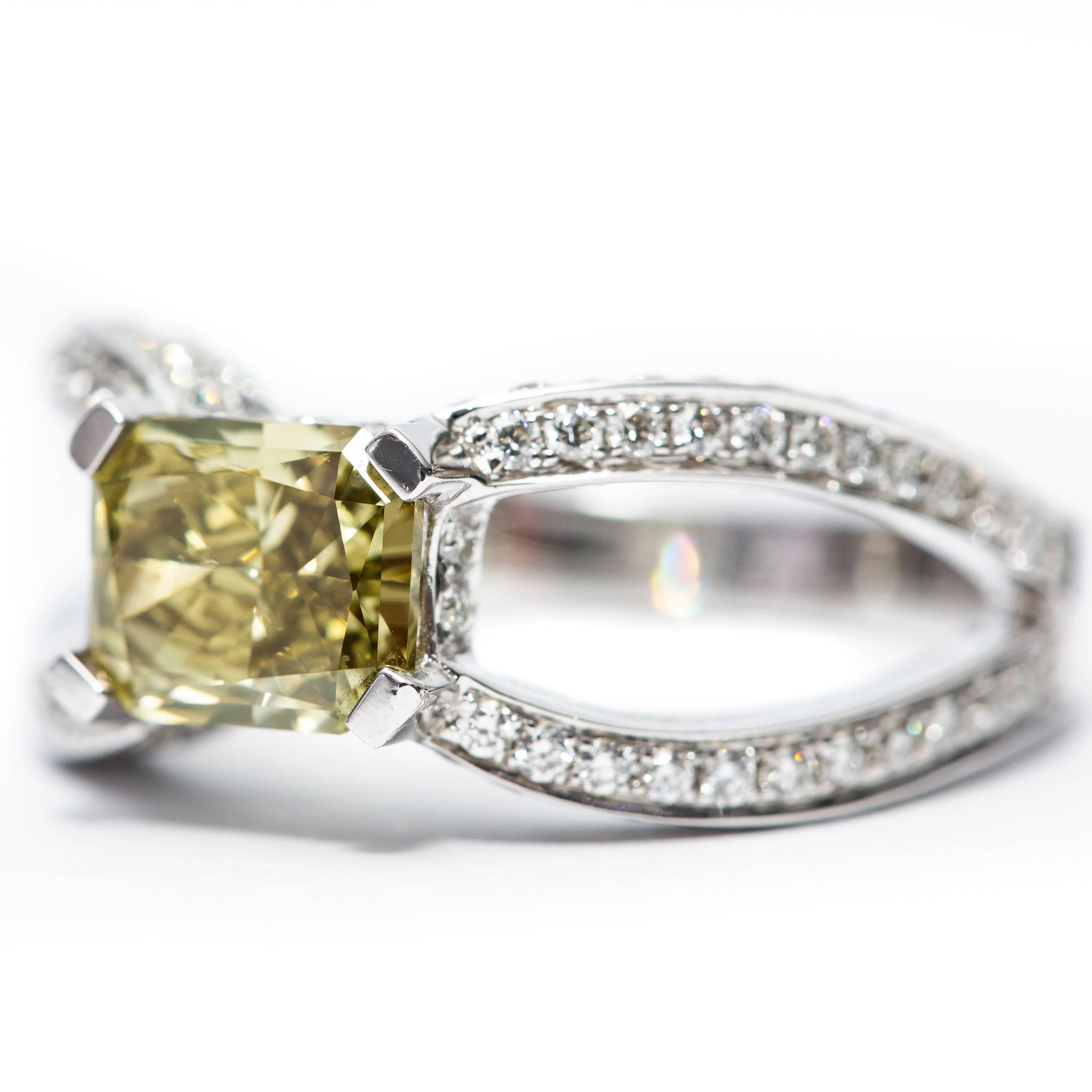 This stunning GIA Certified 1.14 Carat Natural Fancy Dark Brown-Greenish Yellow Radiant Cut - Cornered rectangular modified Diamond situated in the center of the ring featuring 0.80 Carat clarity SI1 with Round Brilliant Diamond down the split Shank