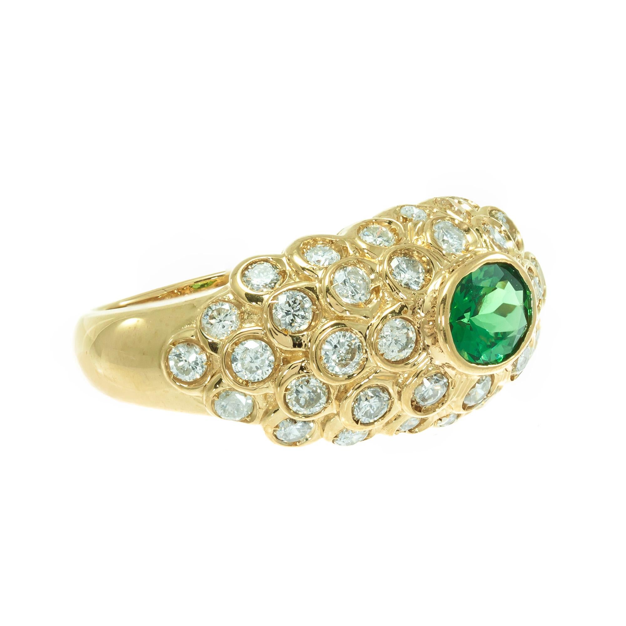 Green tsavorite garnet and diamond cluster cocktail ring. 14k yellow gold dome setting with oval green tsavorite center stone surrounded by a cluster of round diamonds. 

1 oval green SI tsavorite garnet, Approximate 1.17ct GIA Certificate #