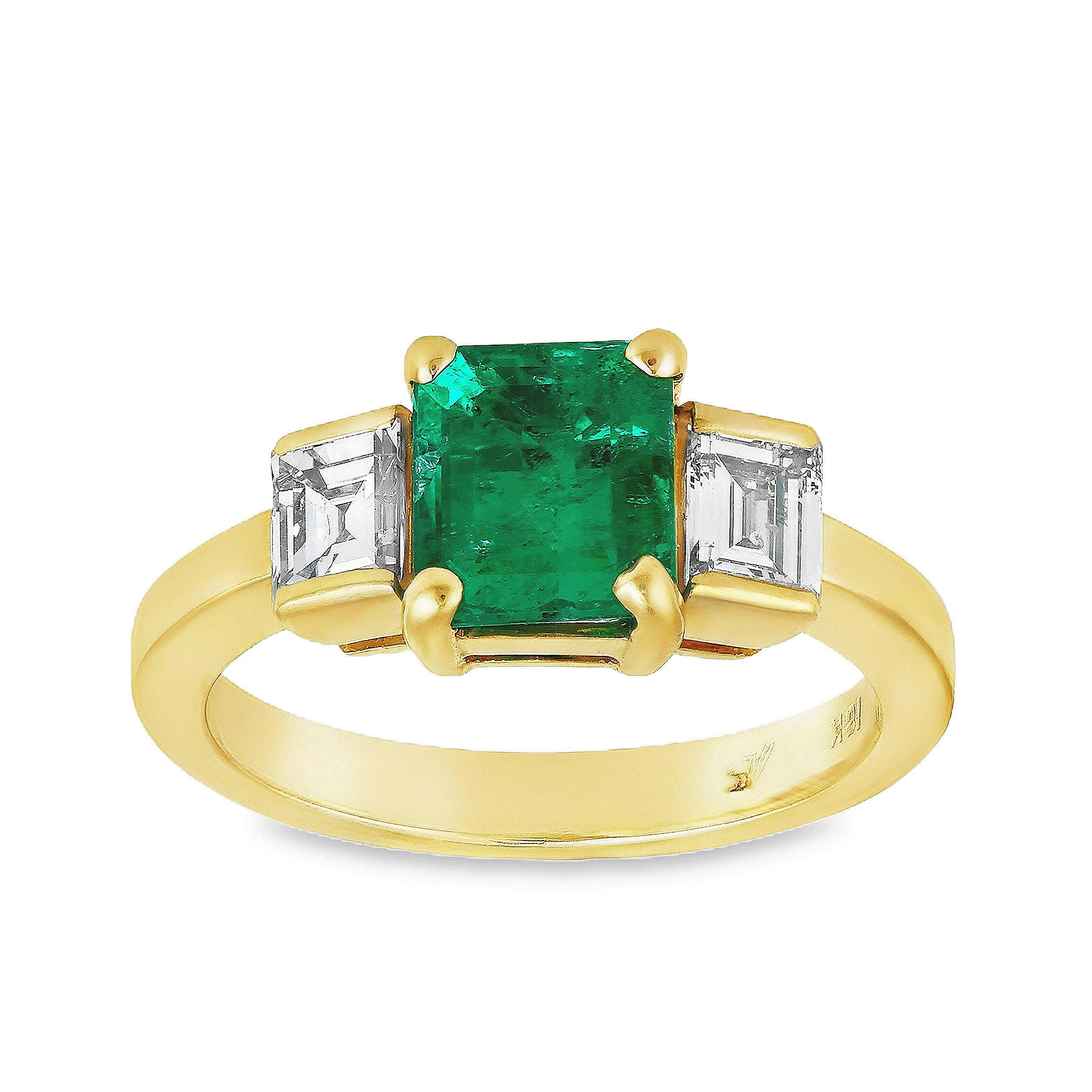 Un delizioso anello di fidanzamento a tre pietre, con uno smeraldo colombiano da 1,17 carati certificato da GIA, incastonato in una classica montatura a quattro punte. Affiancato da piccoli diamanti taglio smeraldo per un peso totale di 0,40 carati.