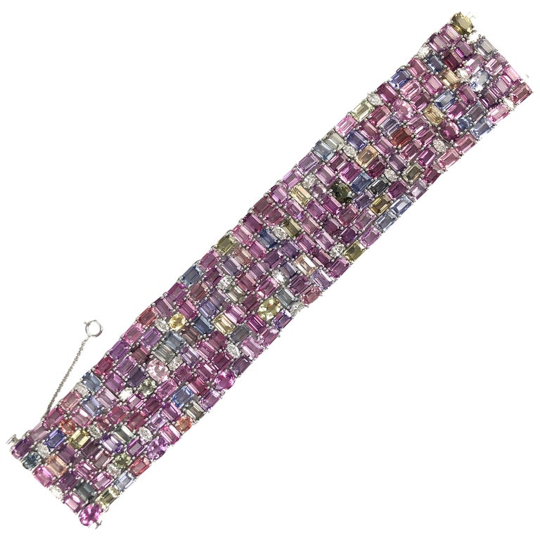 This beautiful bracelet features 119.06 carats emerald cut and oval cut sapphires, including pink, yellow, green, lavender, and light blue. 3.68 carats marquise cut diamonds are tucked inside the densely packed array.
The bracelet measures 7