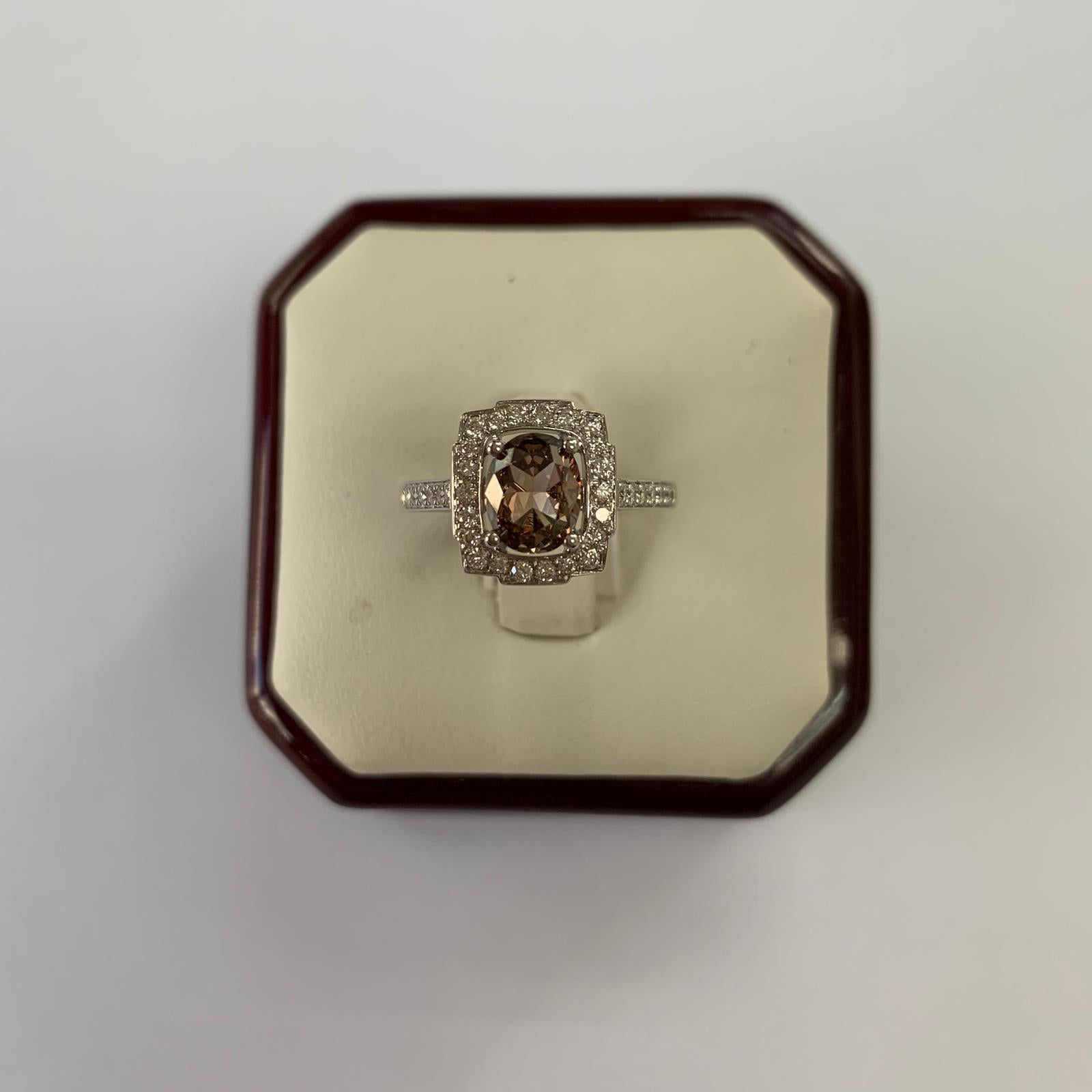 Natural Fancy Dark Orangy Brown Oval Shape Diamond Weighing 1.20 carats by GIA.  Half way paved white diamonds in the halo setting. Its transparency and luster are excellent. set on 18K white gold, this ring is the ultimate gift for anniversaries,