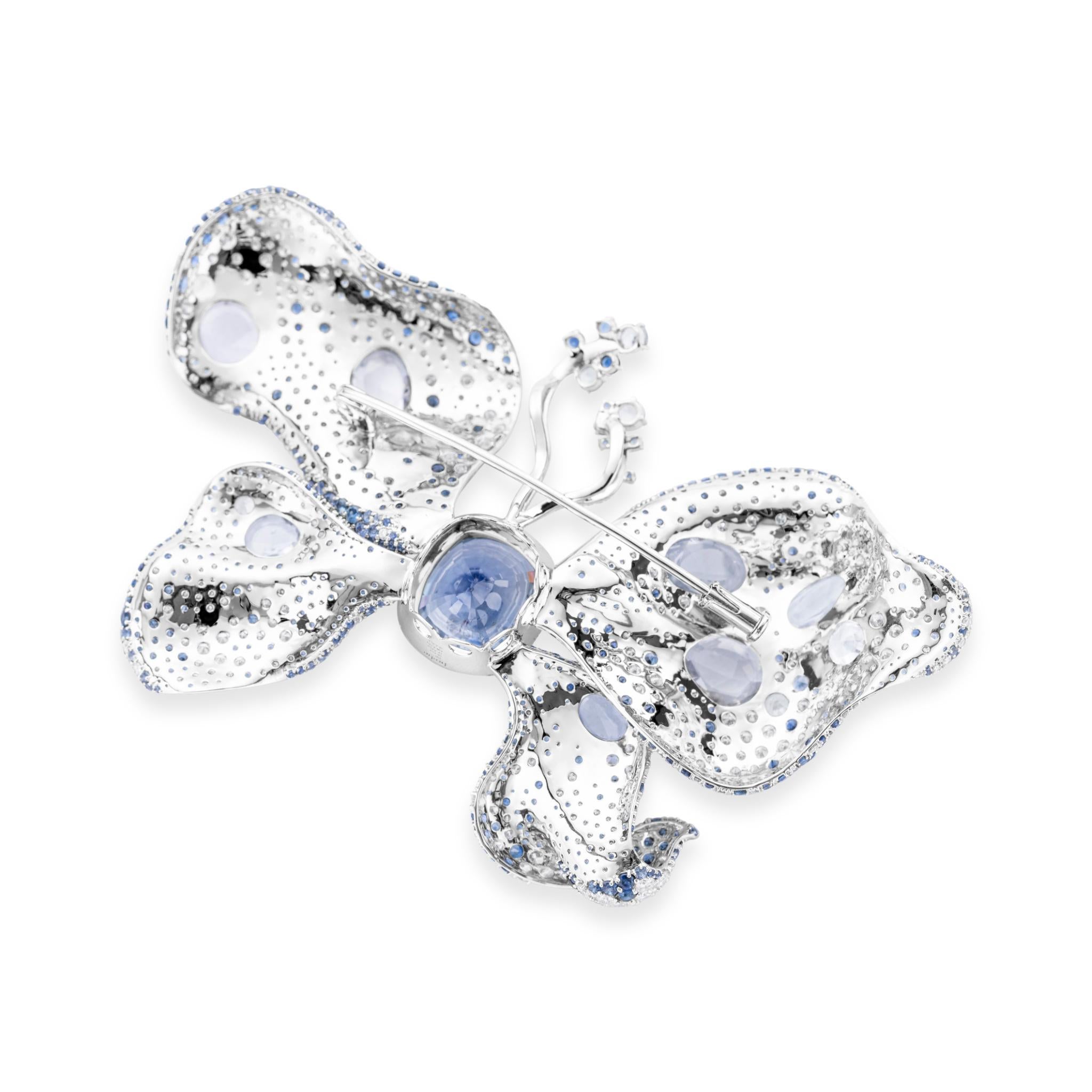 At its heart lies a stunning 12.01 carat cabochon-cut natural blue sapphire, set in 18 carat White Gold. The butterfly's delicate wings sparkle with a constellation of diamond and sapphire melee, creating a dazzling interplay of light and colour.