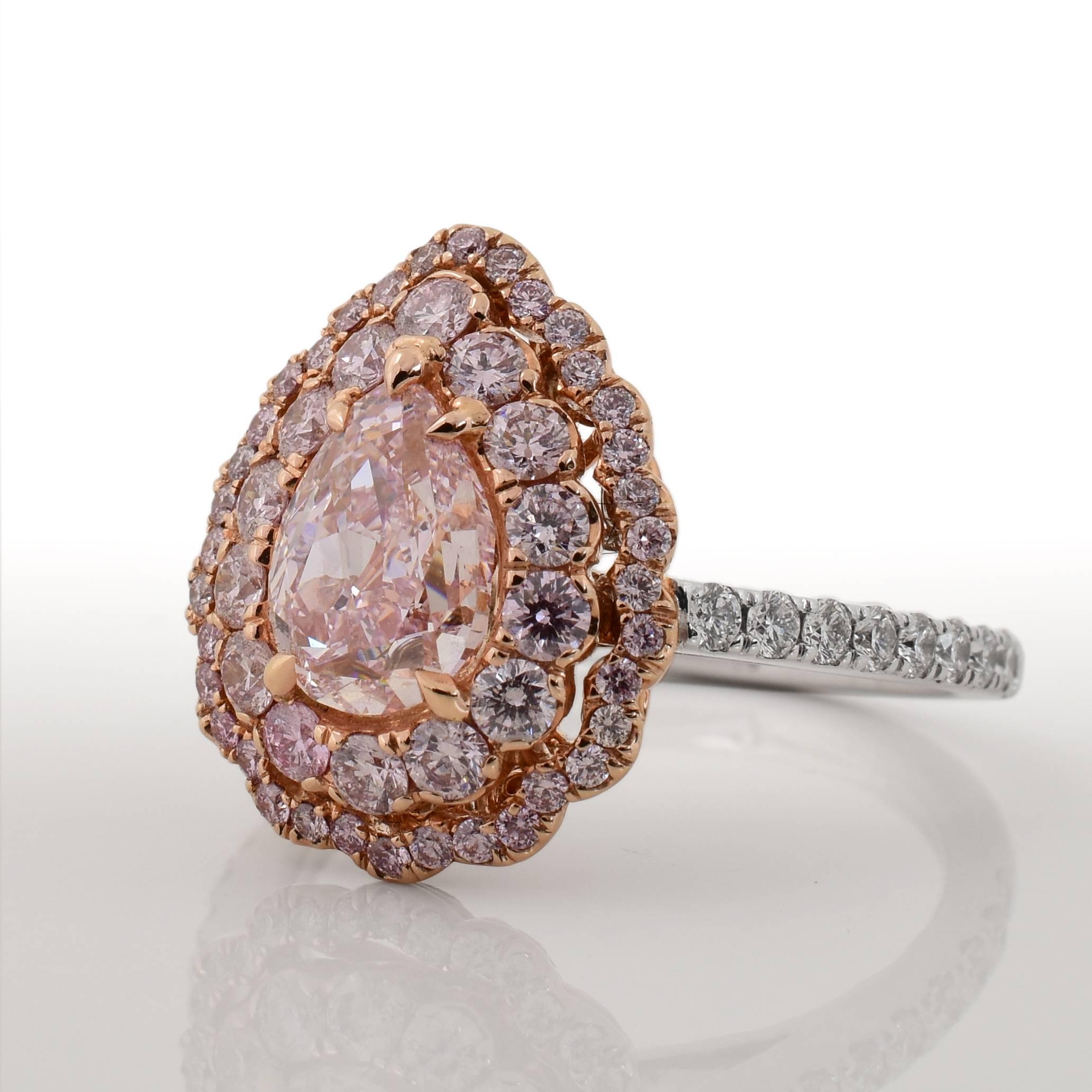 This 18k gold ring features a GIA certified 1.21 carat fancy purplish pink pear shaped diamond center stone. The stone is surrounded by two rows of pink accent diamonds, weighing 0.77 carats total. There are 0.29 carats of white diamonds adorning