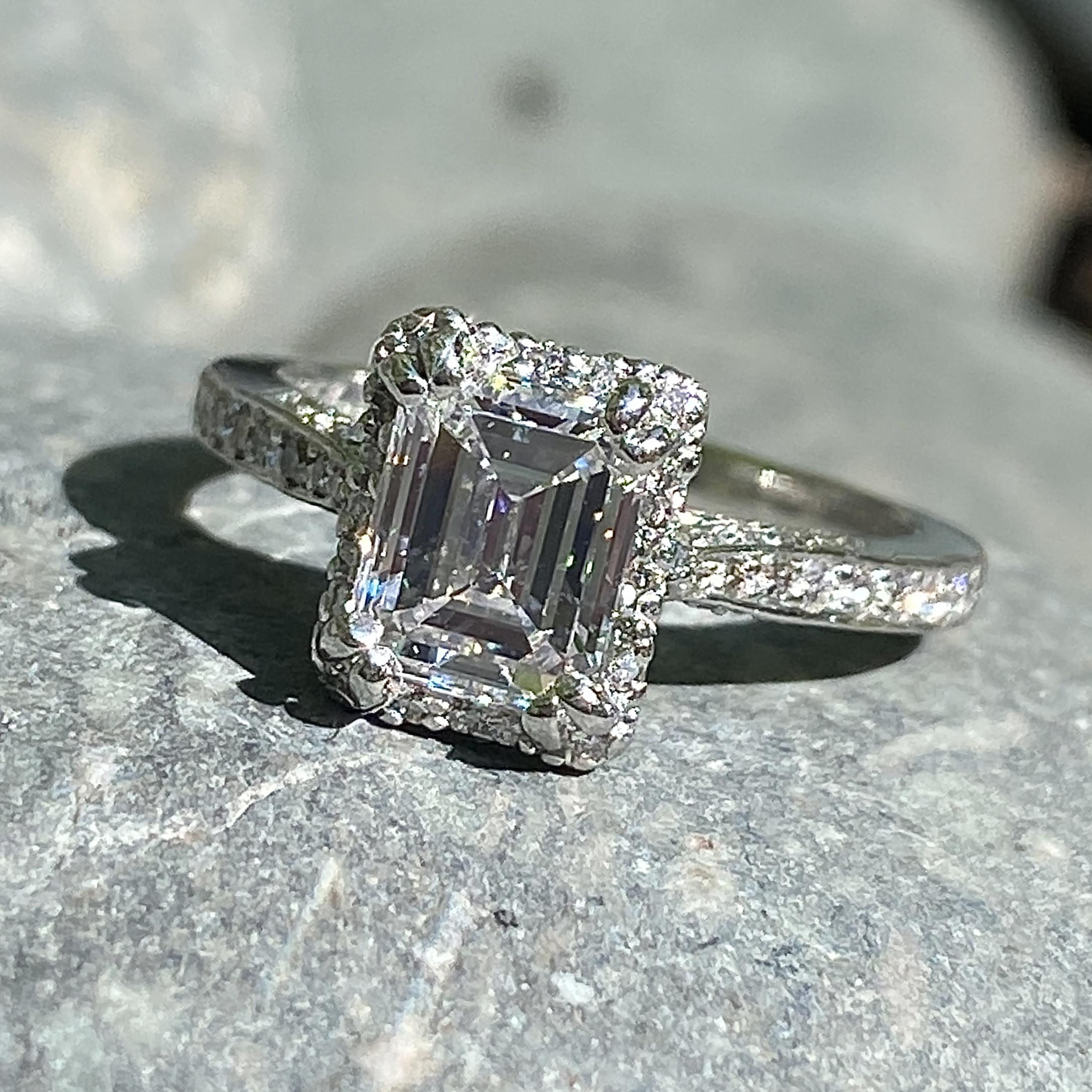 A balanced and elegant platinum setting by Tacori sets the perfect stage for this clean and bright 1.24 carat diamond. 

The setting is a rectangular halo style with the supporting diamonds set at a lower elevation to enhance the brilliance of the