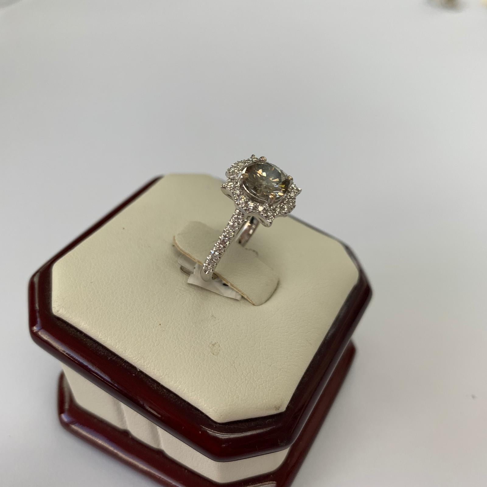 Fancy dark gray round natural diamond weighing 1.24 carats by GIA. surrounded by paved white diamonds in the halo setting. Its transparency and luster are excellent. set on 18K white gold, this ring is the ultimate gift for anniversaries, birthdays,