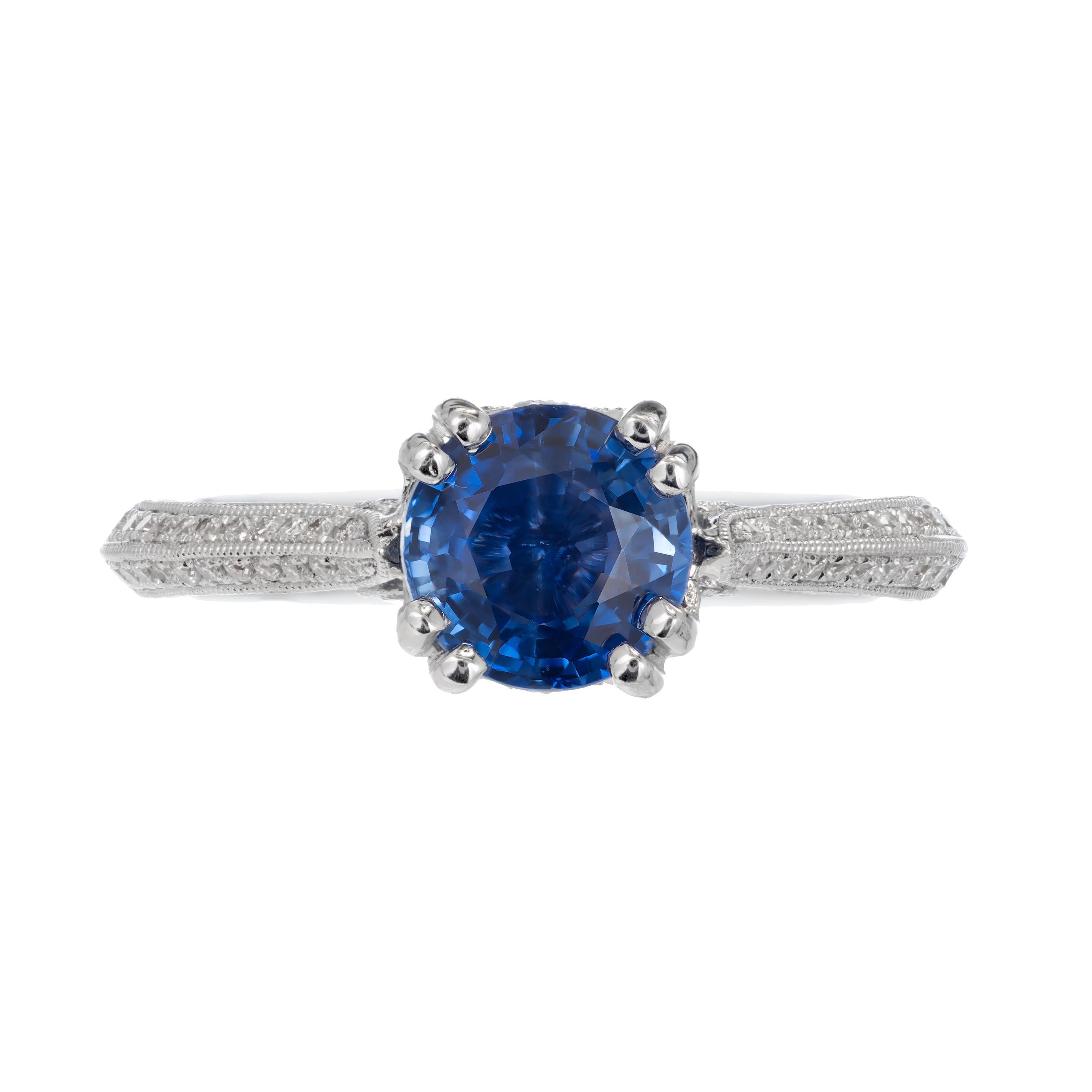 14k White gold sapphire and diamond engagement ring. Bright blue round sapphire is set in 14k white gold double prong head with mil-grain design. Bezel set with round diamonds on each side. The band consists of two rows of pave set diamonds