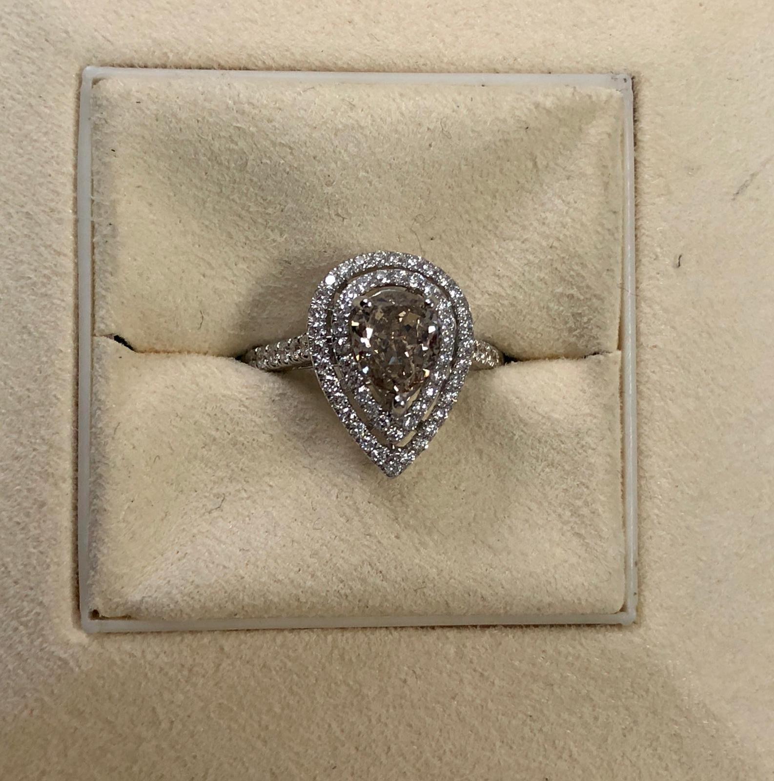 Fancy Light Yellowish Brown natural pear shape diamond weighing 1.28 carats by GIA.  Half way paved white diamonds in the double row halo setting. Its transparency and luster are excellent. set on 18K white gold, this ring is the ultimate gift for