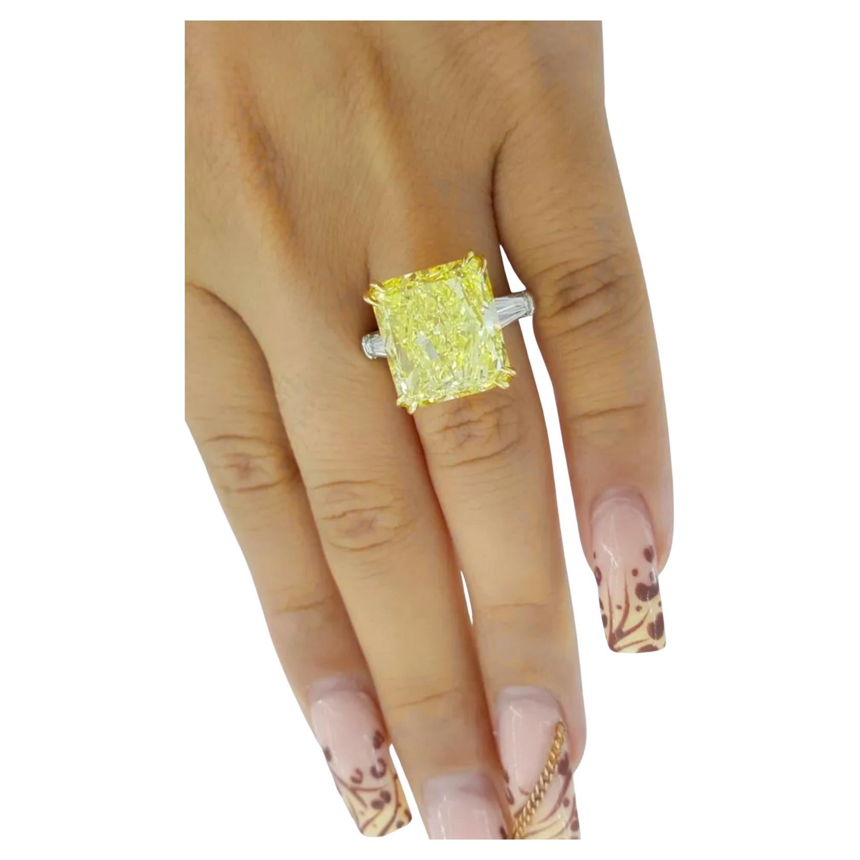  Rectangular Radiant Cut diamond weighing 12.87 ct, with a Fancy Intense Yellow color, VS1 clarity, good polish, good symmetry, and no fluorescence. Its measurements are 13.75 x 12.46 x 7.55 mm.

Accompanying the center stone are two Natural Tapered