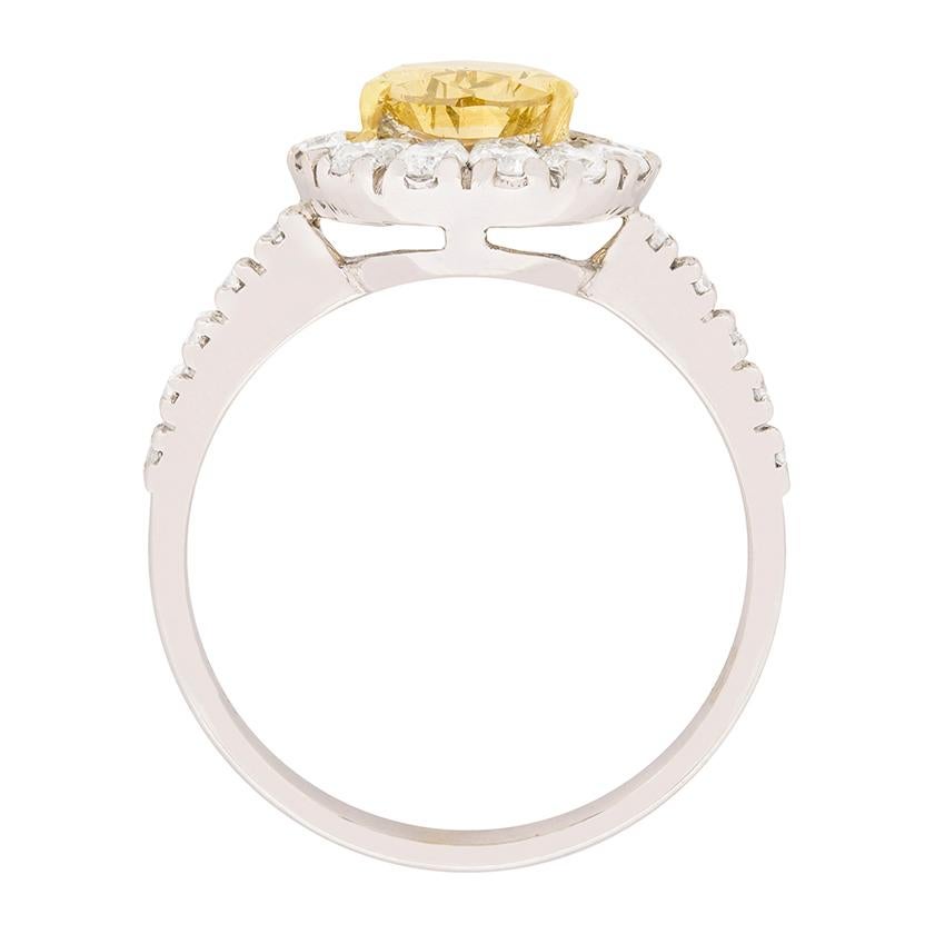 A sparkling 0.75 carat white border of round brilliant cut diamonds frames a distinctive, GIA certified, 1.29 carat, natural fancy colour, pear-shaped diamond at the centre of this unique two-tone diamond engagement ring. The white diamonds are G in
