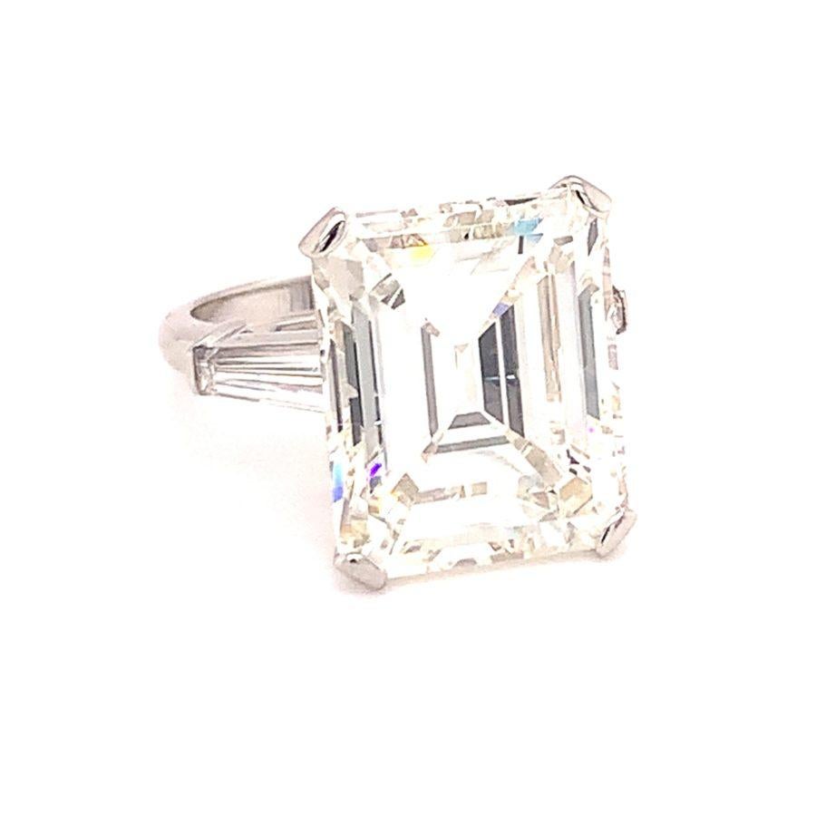 One GIA certified 12.94 ct. diamond engagement ring in platinum centering one emerald cut diamond weighing 12.94 ct. with GIA Report No. 2215083471 – Color L and Clarity VS-1. The featured stone is flanked by two baguette diamonds weighing
