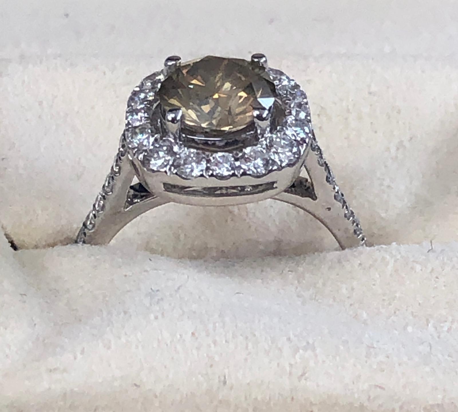 Fancy light yellowish brown natural round diamond weighing 1.30 carats.  Half way paved white diamonds in the halo setting. Its transparency and luster are excellent. set on 18 Karat white gold, this ring is the ultimate gift for anniversaries,