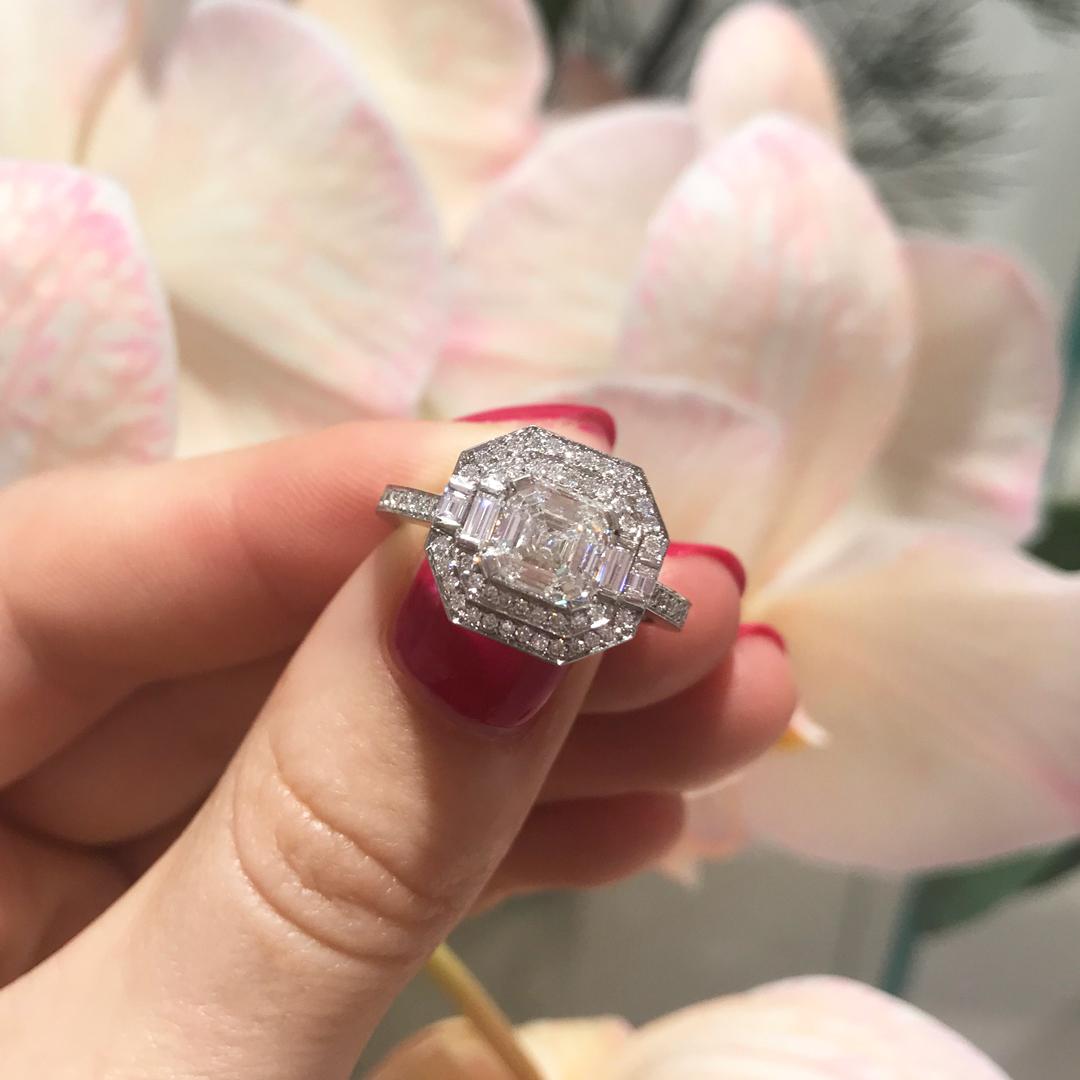 This stunning Matthew Ely engagement ring features a 1.31ct Asscher Cut Diamond (color F clarity SI1) encased between two halos of white Diamonds and finished with a Divine micro pave Diamond set platinum band (total weight 0,47ct color FG clarity