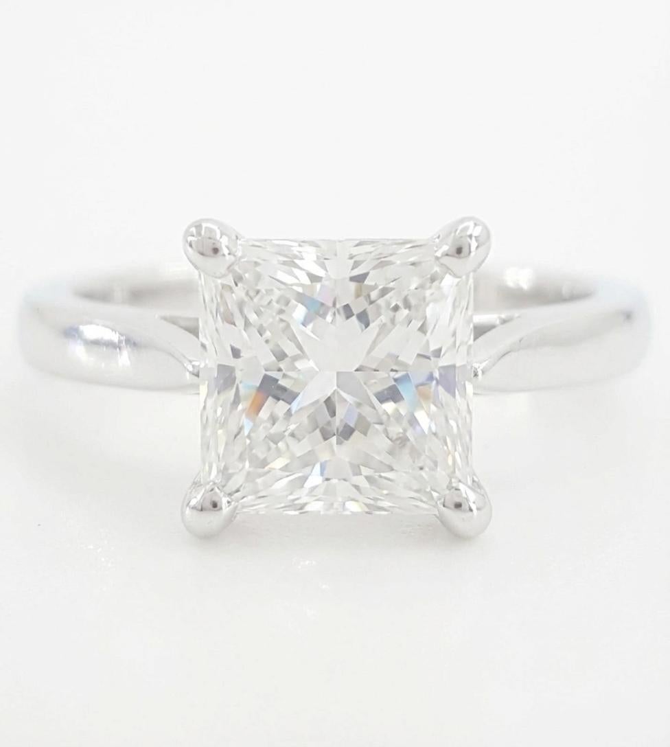 Este elegante anillo de compromiso de oro blanco de 14 quilates incluye un impresionante diamante natural de talla princesa brillante de 1,31 quilates, certificado por el GIA. La piedra central es de un excepcional color D (incolora) y claridad VS2,
