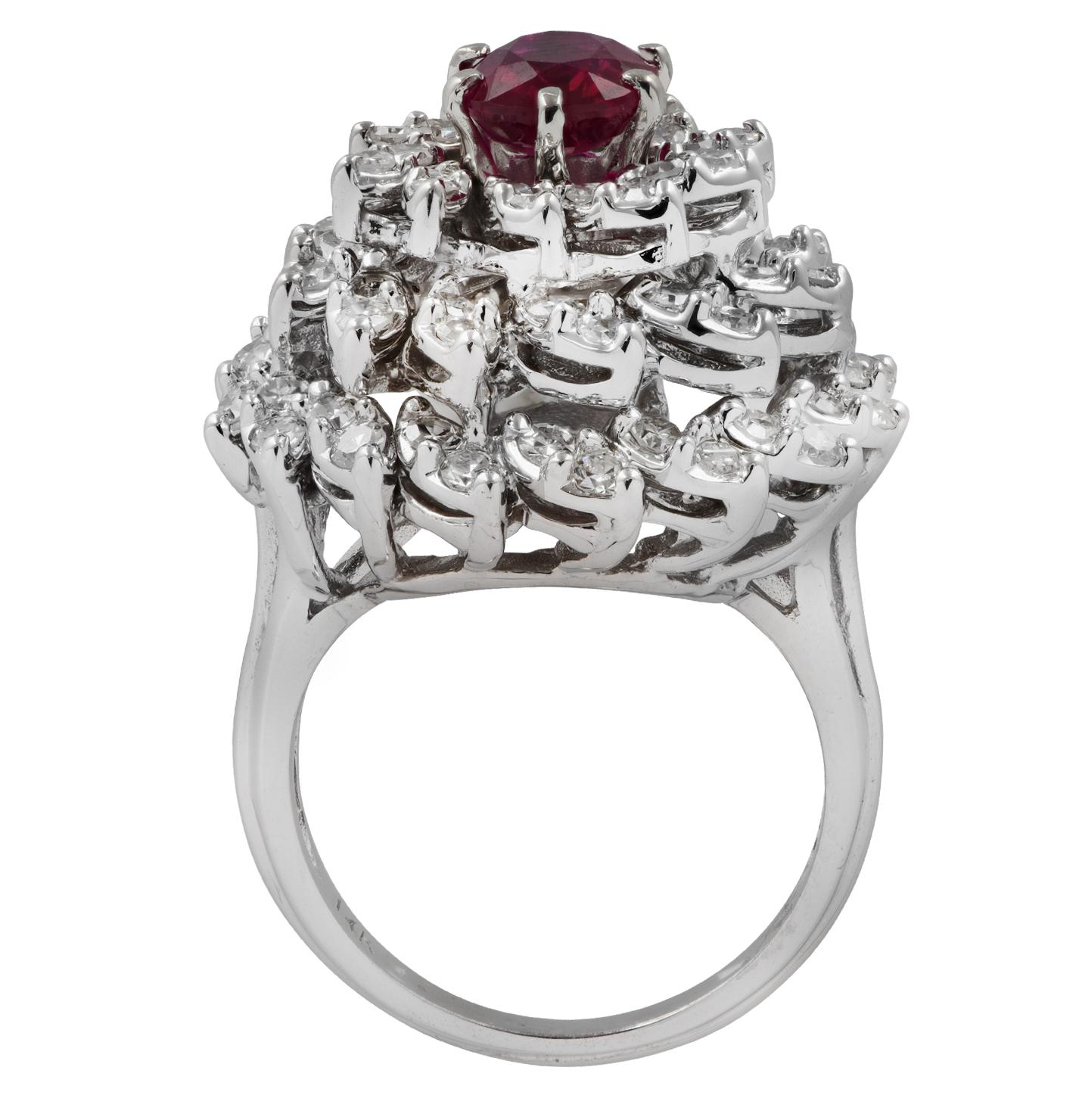 Spectacular cocktail ring crafted in white gold showcasing a GIA Certified oval ruby weighing 1.31 carats resting on a dome of 75 round brilliant cut diamonds weighing approximately 1 carat total, G color, VS clarity. The face of the ring measures