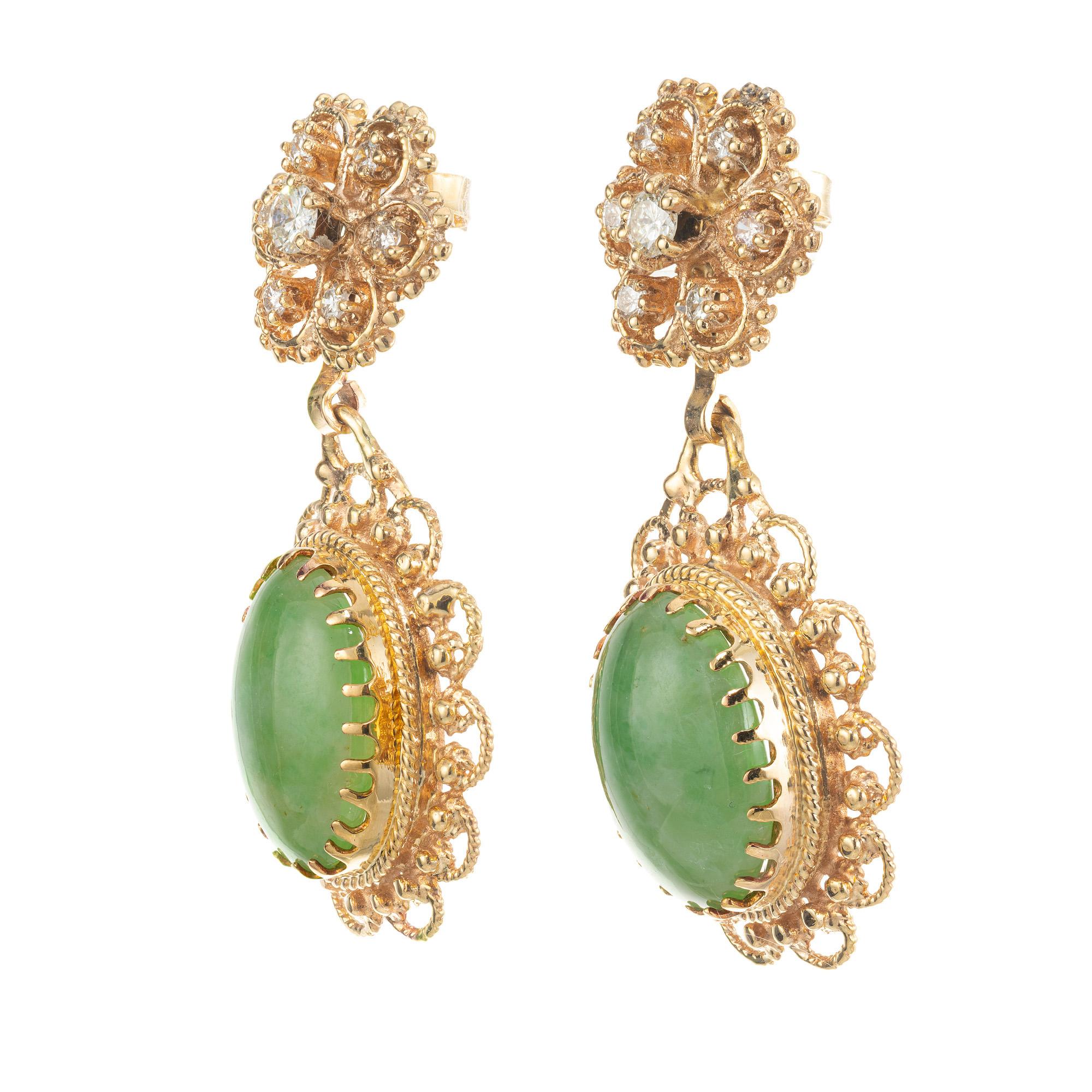 Natural untreated 1950's jadeite jade and diamond earrings. These spectacular mid-century earrings begin with 2 oval cabochon jade gemstones with a total carat weight of 13.20cts. which are set in 14k yellow gold. Each jade dangle is accented by 7