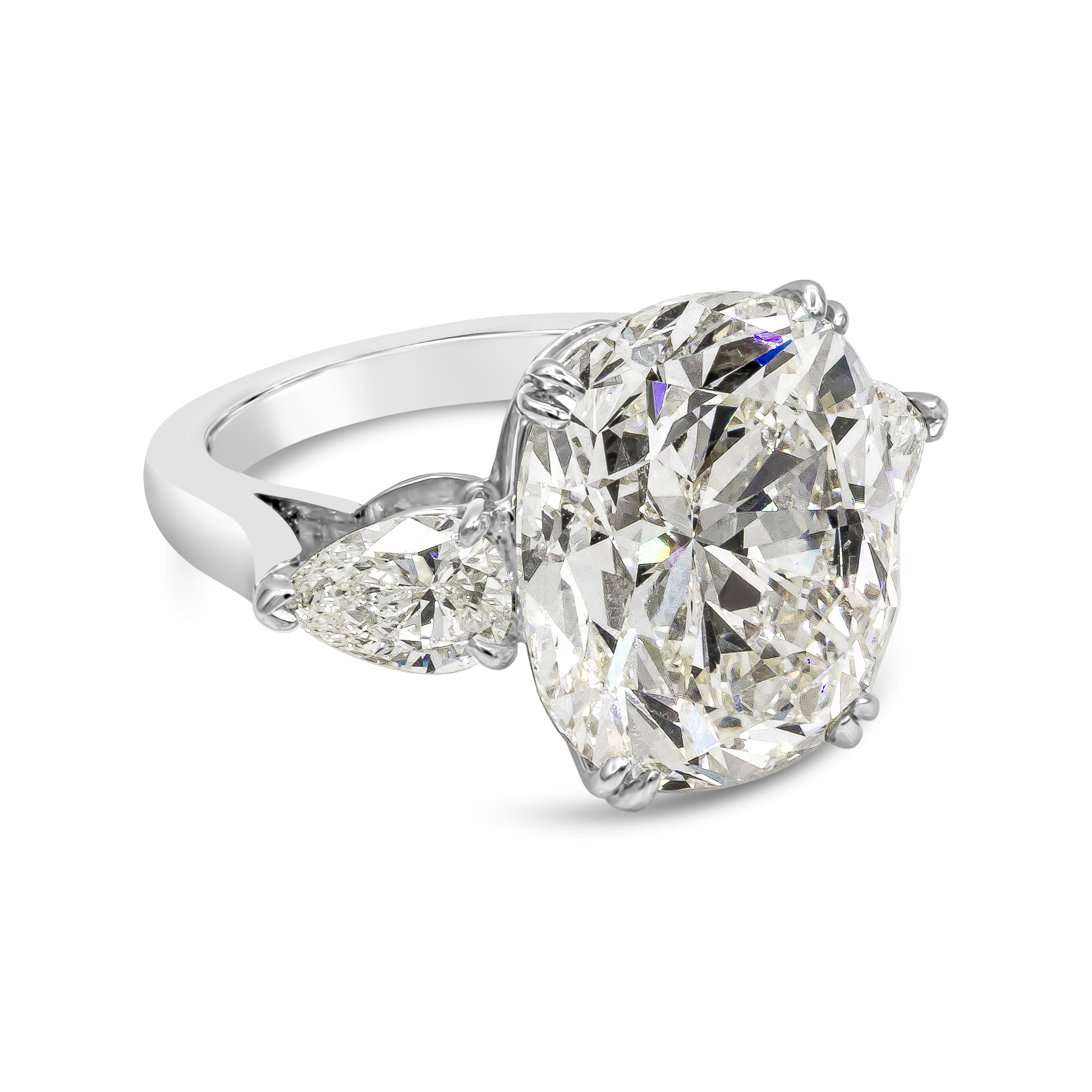 An important and modern engagement ring style showcasing a 13.23 carat cushion cut diamond certified by GIA as K color and SI1 in clarity. Flanking the center diamond are two brilliant pear shape diamonds weighing 1.52 carats total. Set in a