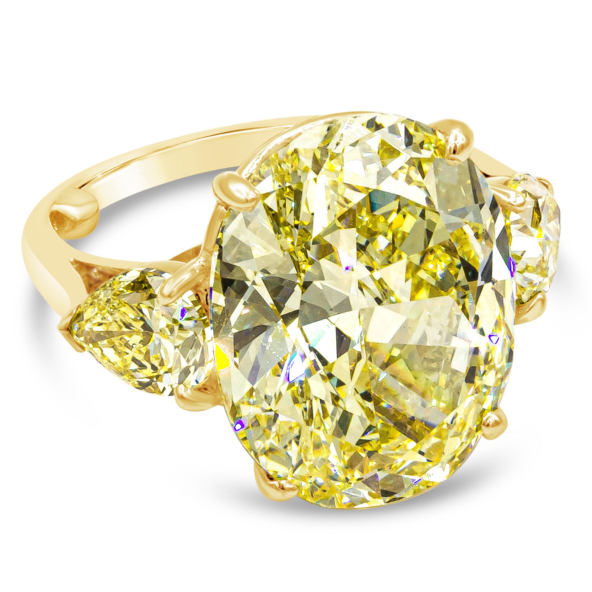 Well crafted color rich three stone engagement ring showcasing a vibrant 13.46 carat oval cut yellow diamond certified by GIA as fancy intense yellow, VS1 clarity, set in a four prong 18k yellow gold basket. Flanking the center stone are two GIA