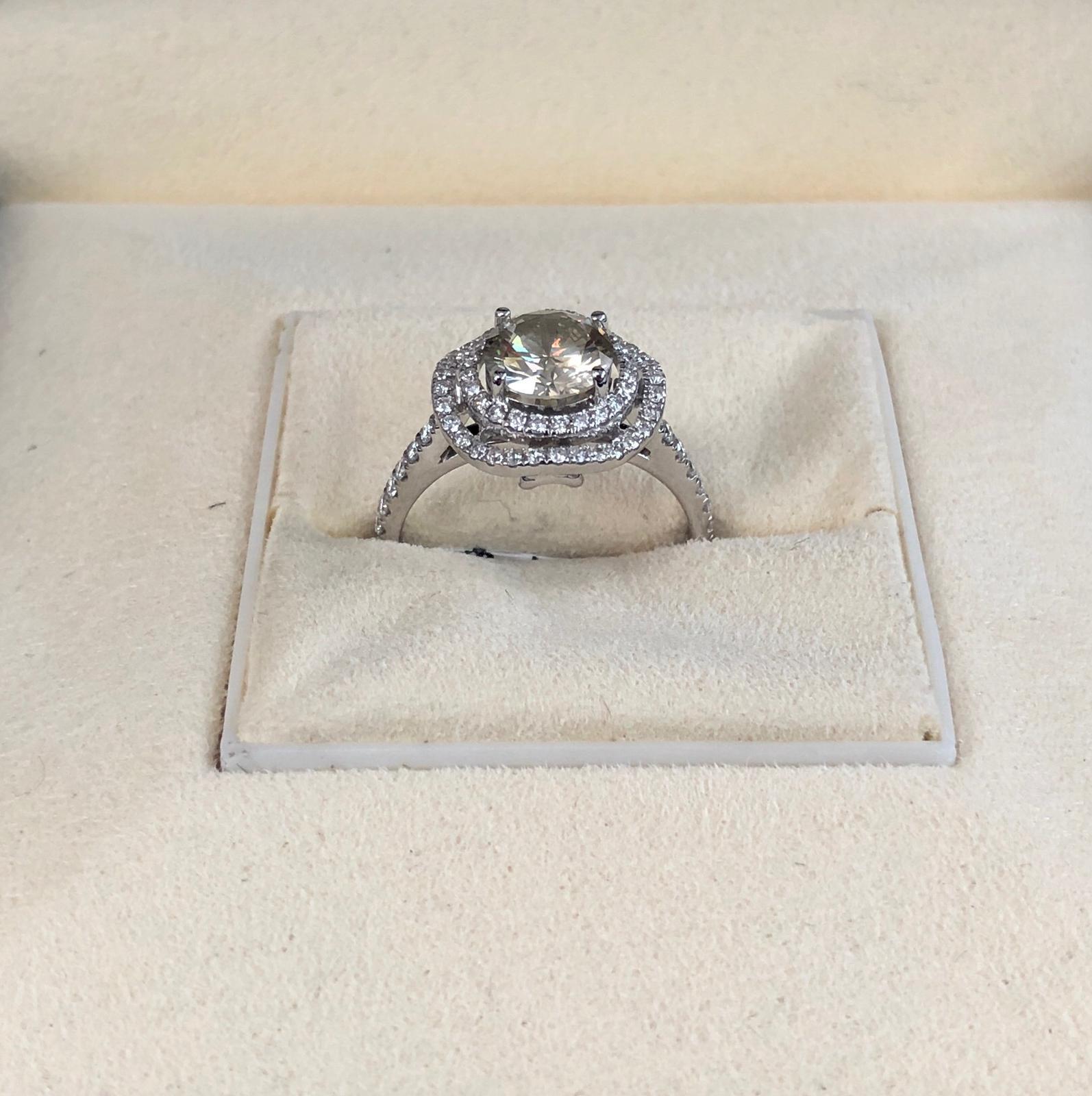 Natural Fancy Greenish Yellow-Brown round diamond weighing 1.35 carats.  Half way paved white diamonds in the double halo setting. Its transparency and luster are excellent. set on 18K white gold, this ring is the ultimate gift for anniversaries,