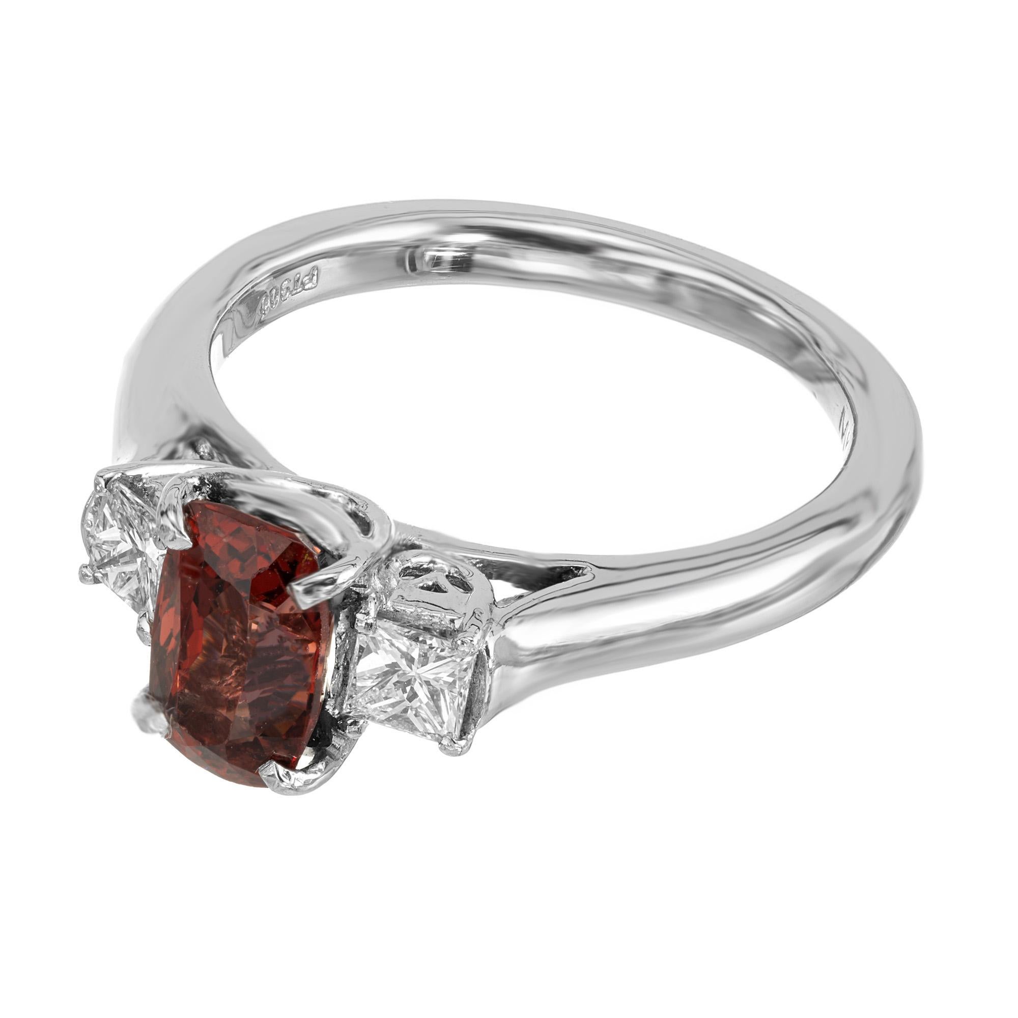 Roter natürlicher, unbehandelter Spinell und Diamant-Verlobungsring mit drei Steinen. Länglicher Spinell mit zwei seitlichen Diamanten im Prinzessschliff in einer Platinfassung.

1 natürlicher orange-roter Spinell im Kissenschliff, Gesamtgewicht ca.