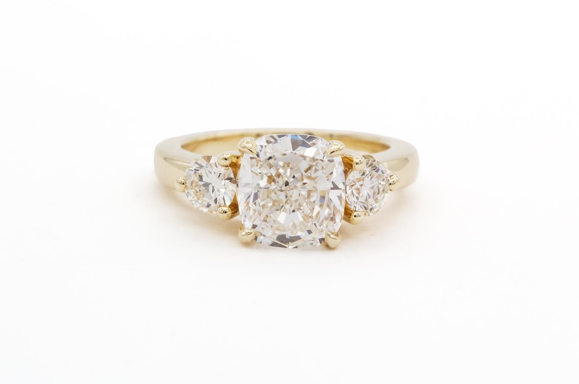 We are pleased to offer this GIA Certified & Laser Inscribed 14k Yellow Gold & Diamond Three Stone Engagement Ring. This beautiful classic ring features a GIA certified 3.10ct H/VS2 cushion cut diamond set in a 14k yellow gold three stone setting