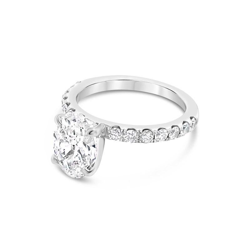 An 18 karat white gold engagement ring featuring a 1.50 carat oval cut natural diamond, D SI2, accented by 0.45 carat total weight in round diamonds that go halfway down the band. This ring is currently a size 4.25 but can be resized upon request.