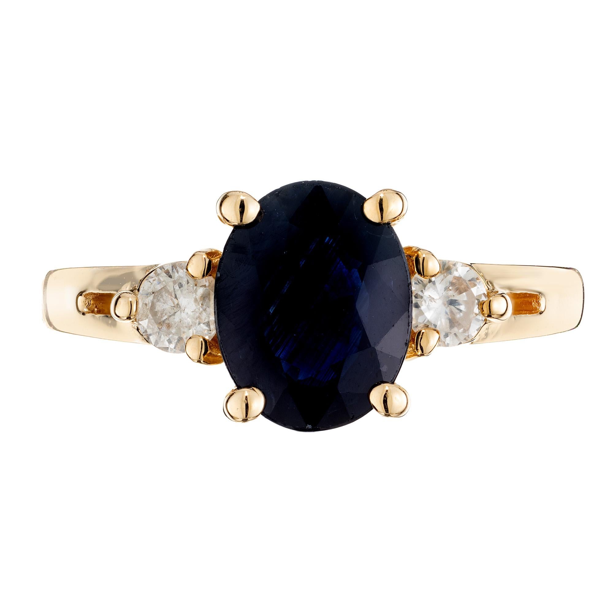 1970's Classic and simple, sapphire and diamond three-stone ring. At the center of this 14k yellow gold setting is an oval 1.50ct sapphire which is accented by two round cut diamonds. The sapphire is a rich deep blue in color and certified by the