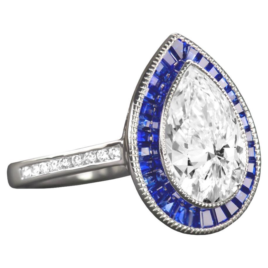Ein exquisiter, handgefertigter blauer Saphir-Halo mit einem 1,50ct GIA-zertifizierten Diamanten im Birnenschliff, der ein lebhaftes Funkeln, ein absolut augenreines Aussehen, eine strahlend weiße F-Farbe und einen glamourösen Schliff bietet. Der