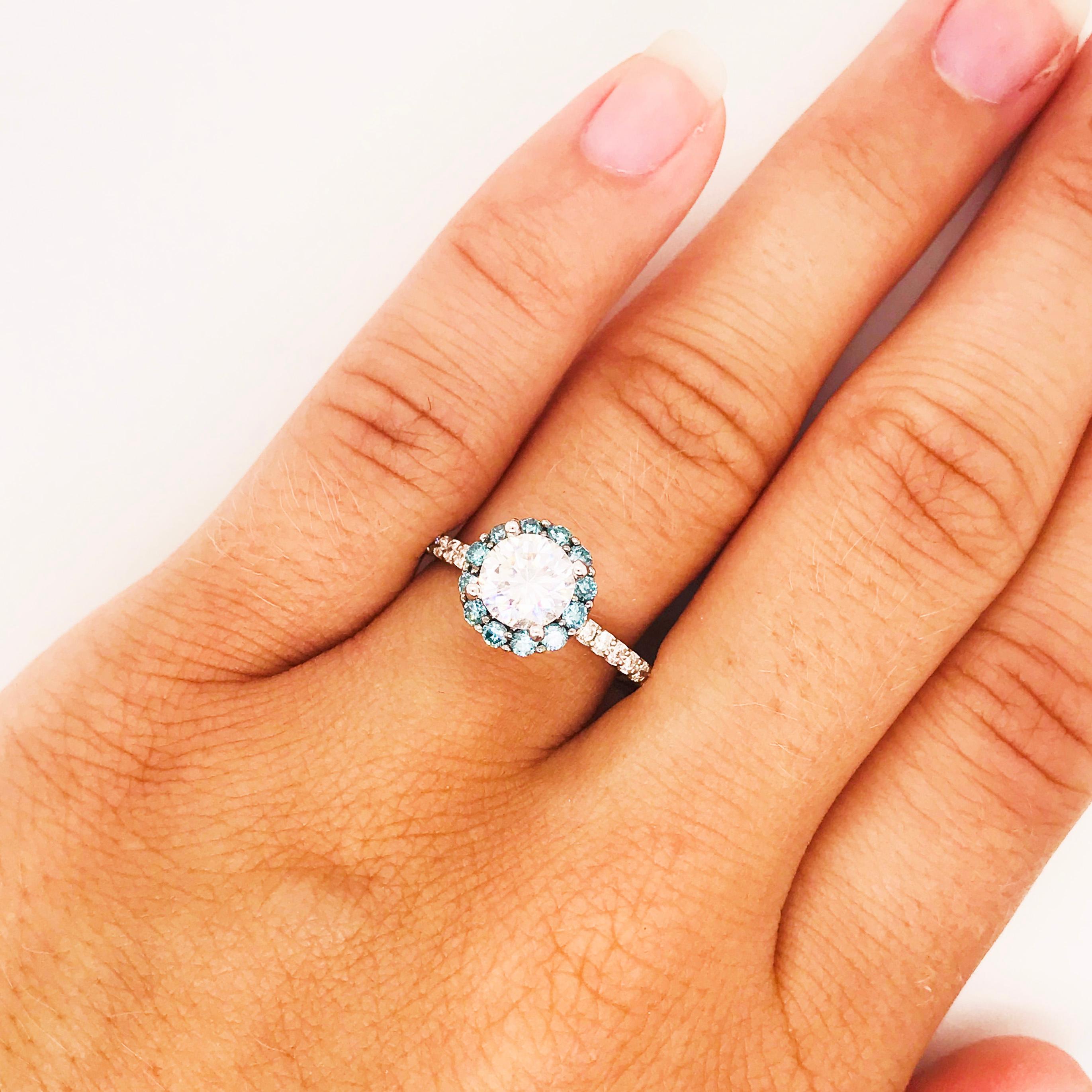 Gorgeous ice blue diamond halo round brilliant diamond engagement ring! This unique ring has a gorgeous round brilliant diamond set in the center of an ice blue diamond halo! The diamond halo is made of round brilliant blue diamonds. There are two