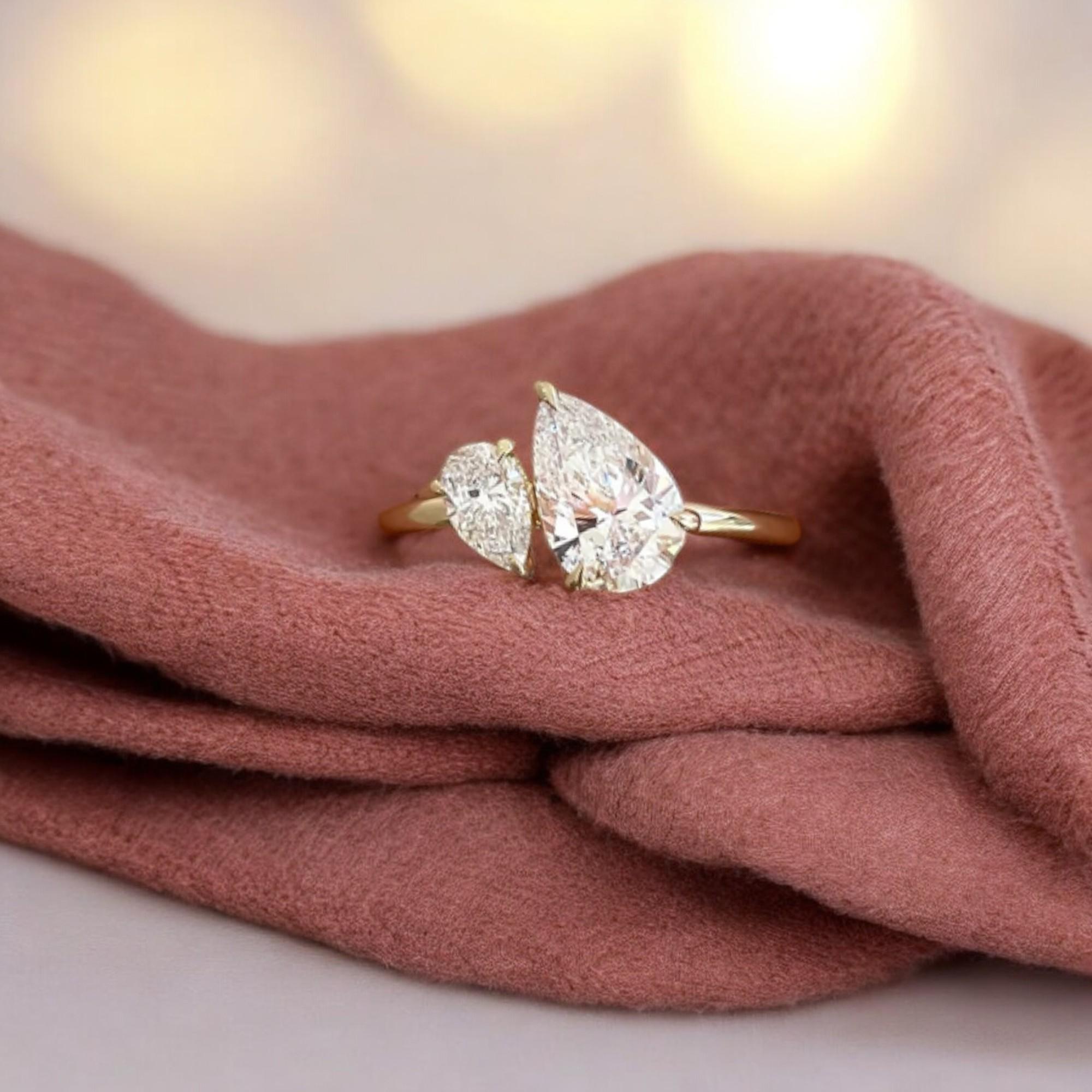 Cette bague en or jaune 18 carats ajoute une touche brillante aux costumes traditionnels. Il présente 1,50 carats de diamants poires F/VS1 certifiés par le GIA dans un superbe design Toi et Moi !

Spécifications : 
Couleur du diamant : blanc
Poids