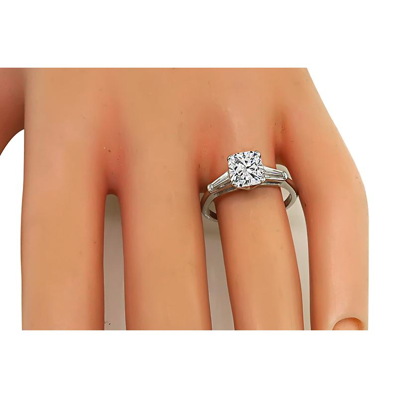 This is an amazing platinum engagement ring. The ring is centered with a sparkling GIA certified cushion cut diamond that weighs 1.50ct. The color of the diamond is J with VS1 clarity. The center diamond is accentuated by dazzling baguette cut
