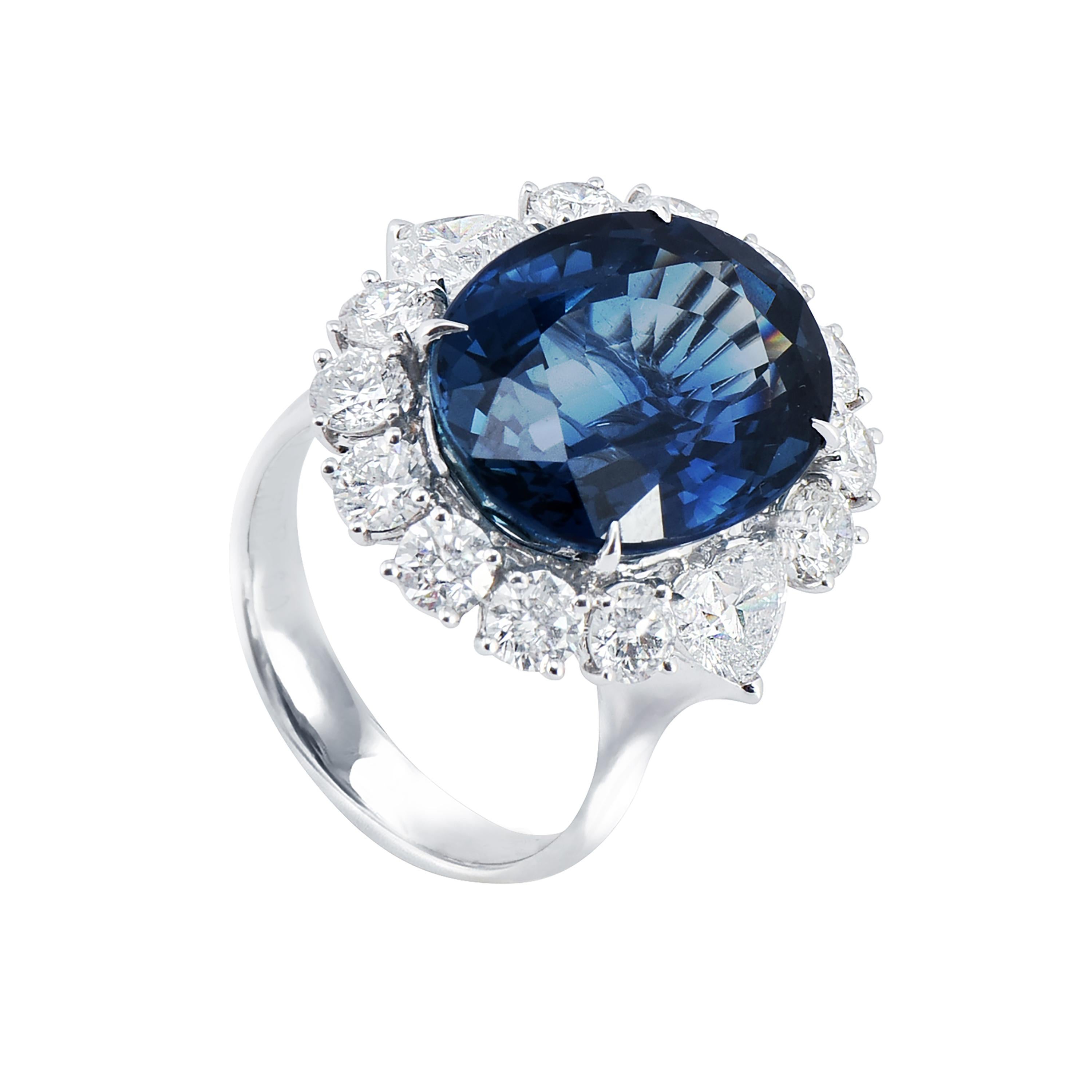 18 karat white gold blue sapphire cocktail ring from the Royal Blue collection of Laviere. The ring is set with a GIA certified 15.12 carats oval shape blue sapphire in the center surrounded by 1.95 carats round brilliant diamonds and two heart