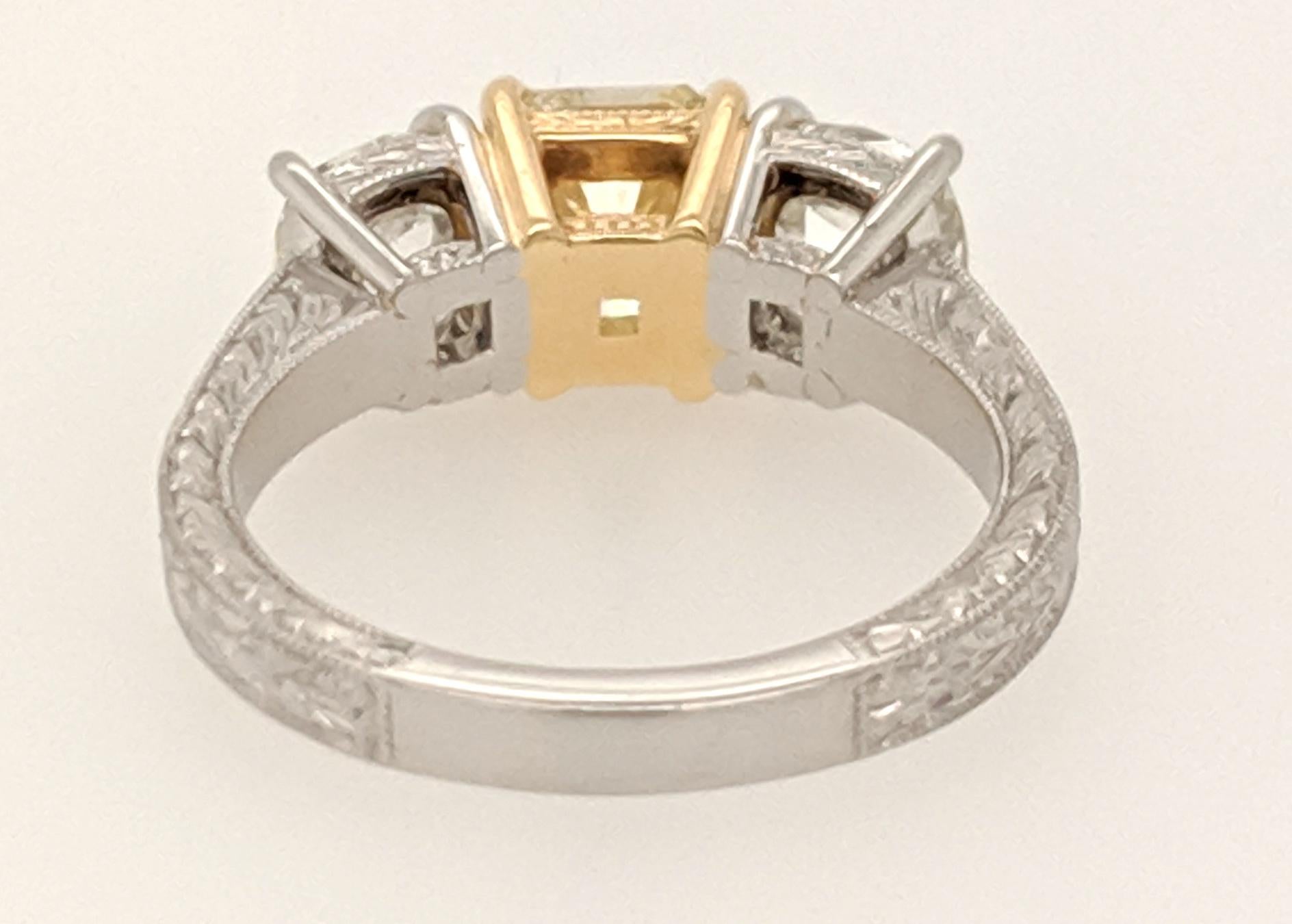 A GIA Certified Diamond 3 Stone ring crafted in Platinum and 18k yellow gold Featuring (1) 1.53ct Cushion Cut Yellow Diamond flanked by (2) old mine cushion shaped diamonds weighing approximately 1.97cttw with a color of 