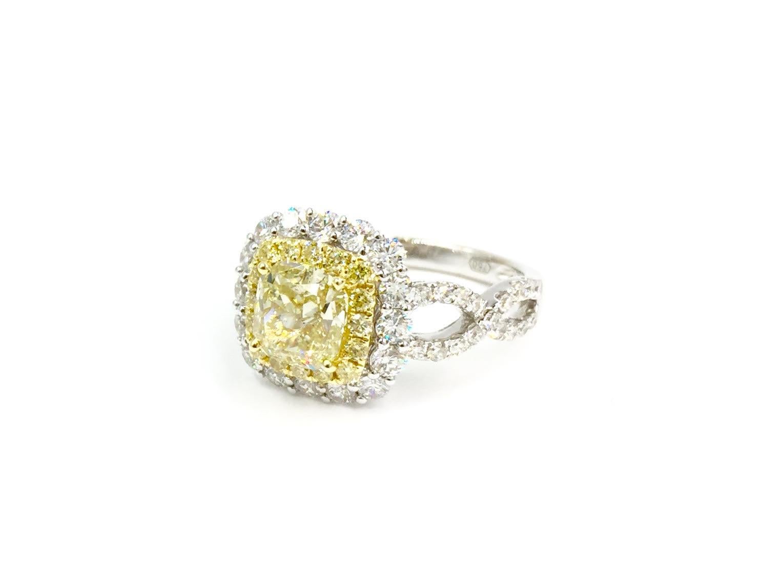 This gorgeous ring by Luca Gems, a high-end jewelry designer specializing in colored diamonds, features a GIA certified 1.55 carat cushion shape natural fancy yellow diamond of SI2 clarity. It is expertly set in an 18 karat gold diamond halo setting