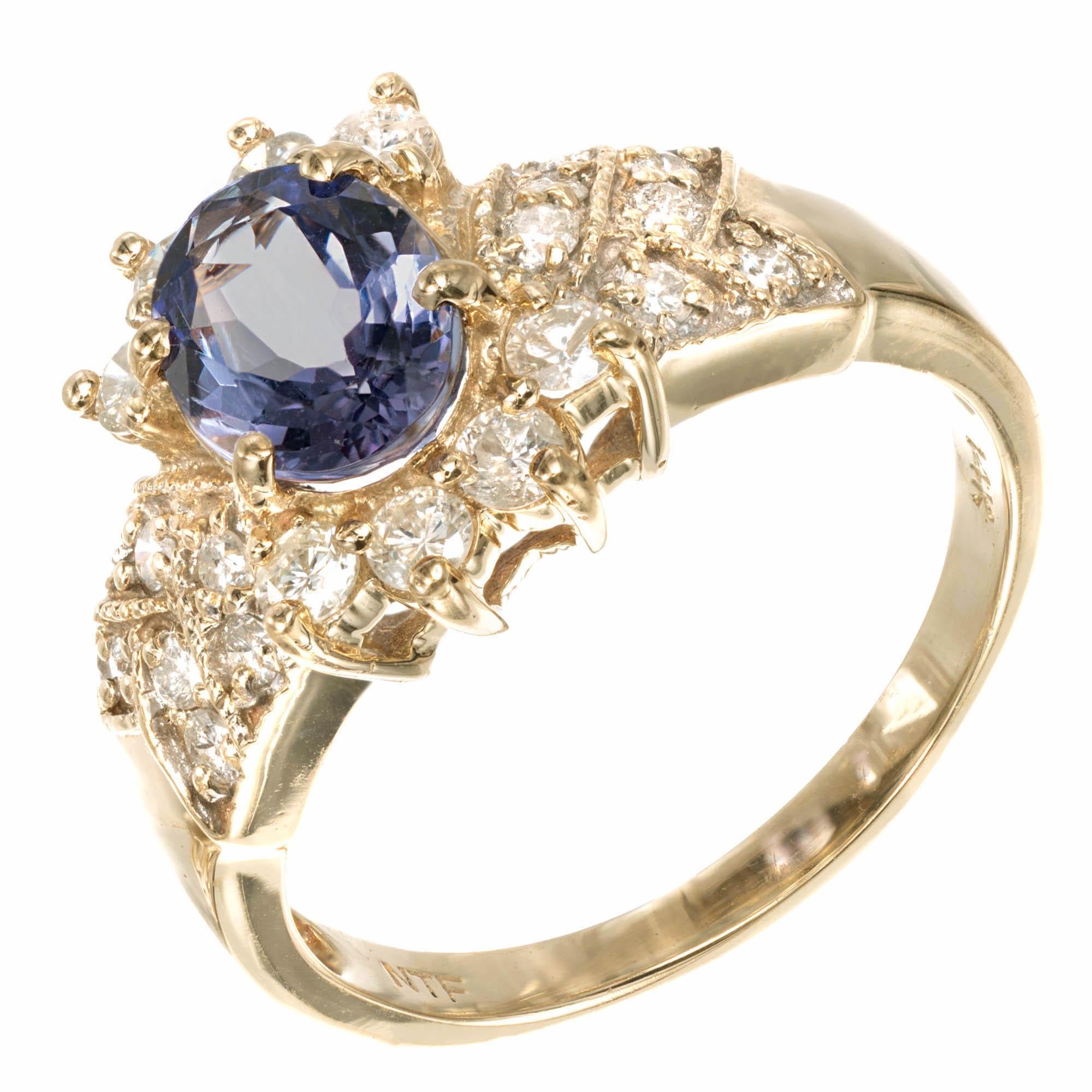  Tanzanite and Diamond halo engagement ring. Oval shaped violet blue Tanzanite set in 14k yellow gold with round brilliant cut Diamonds prong set at the top and bottom of the oval with additional round Diamonds Pavé set with a criss cross mil-grain