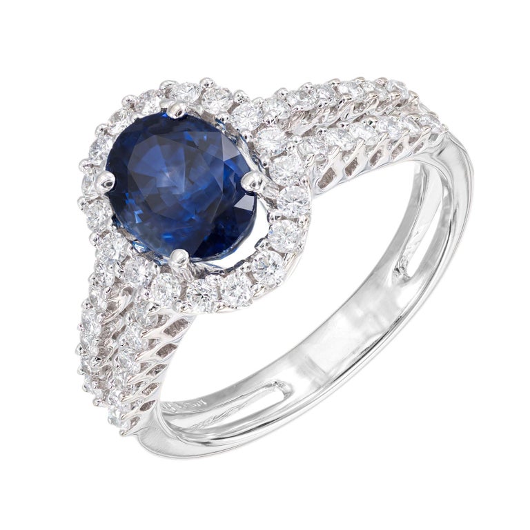 Blue sapphire and diamond engagement ring. GIA certified oval 1.65ct center stone with a halo of round diamonds in a 18k white gold double shank setting. 

1 oval blue sapphire, SI approx. 1.65cts GIA Certificate # 2205989557
42 round brilliant cut
