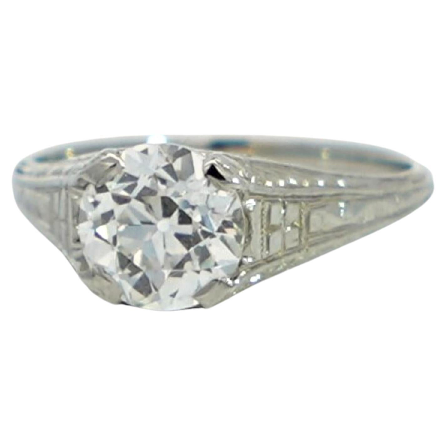 This vintage Art Deco engagement ring, crafted circa 1940, exudes timeless elegance and sophistication. Made from exquisite 20K white gold, the ring features intricate filigree work on the band, adding a touch of vintage charm. The centerpiece of