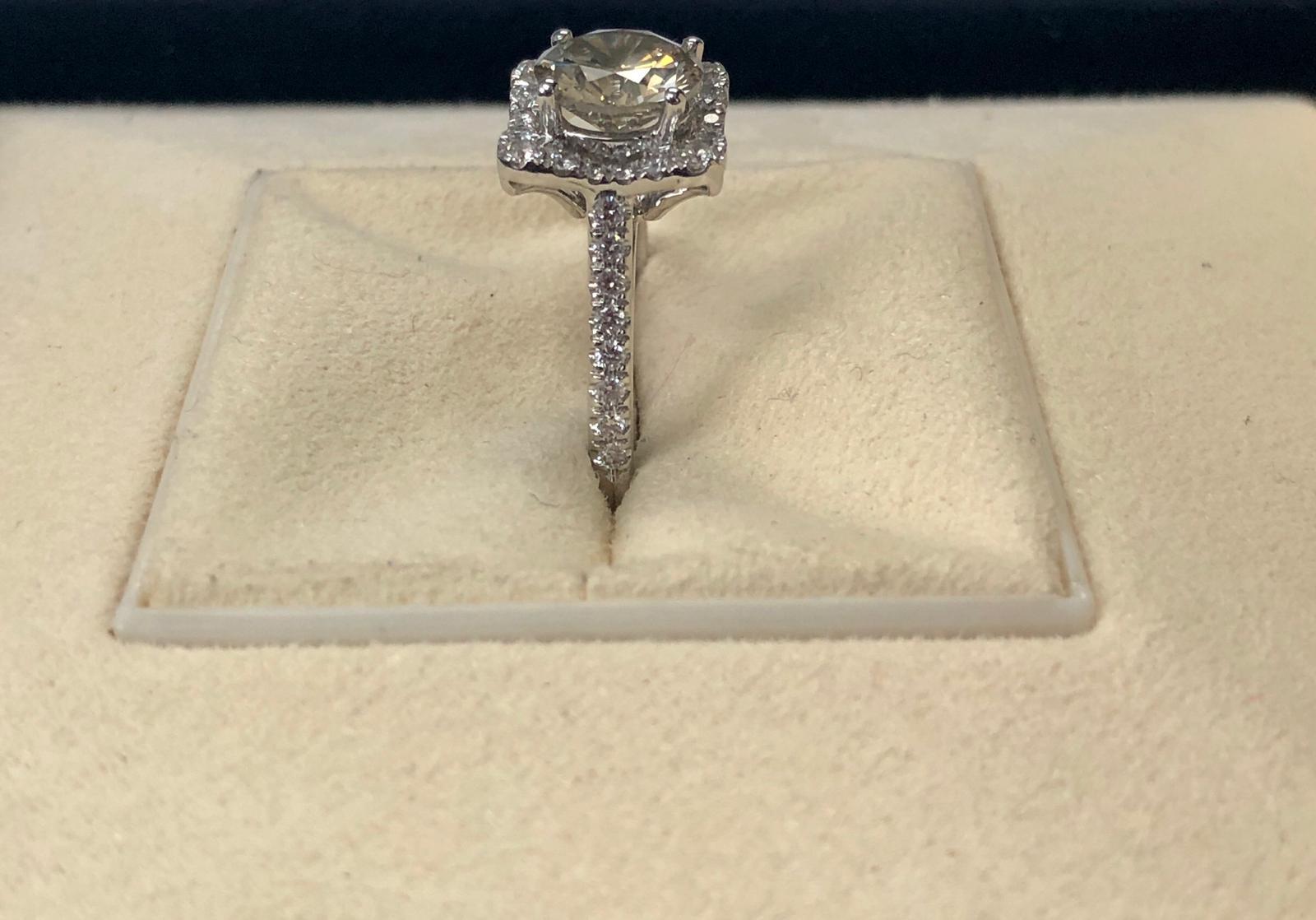 This is a natural fancy brown-greenish yellow natural round diamond weighing 1.70 carats by GIA.  Half way paved white diamonds in the halo setting. Its transparency and luster are excellent. set on 18K white gold, this ring is the ultimate gift for