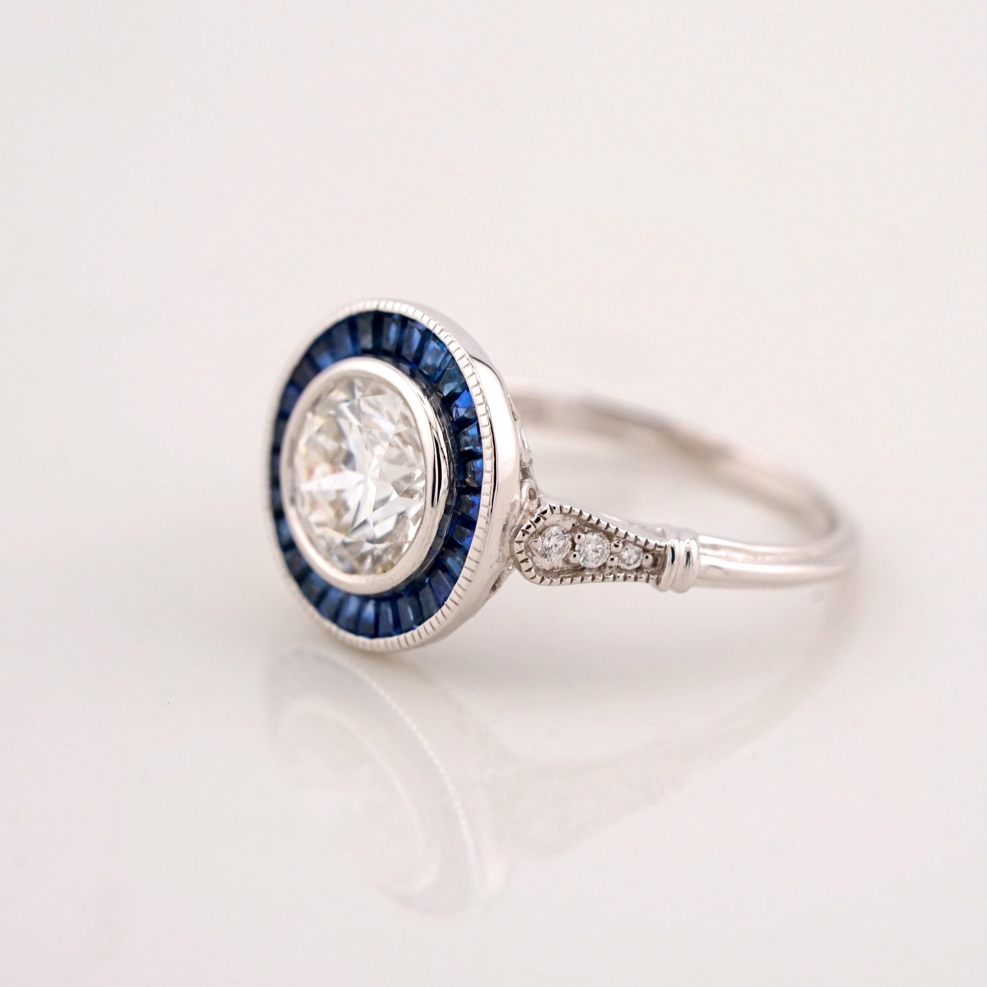 This elegant ring features a 1.74 carat round brilliant diamond, GIA certified with excellent cut, VVS2 clarity, and F color. The diamond is encircled by a vibrant halo of French-cut blue sapphires, meticulously arranged in a striking Art