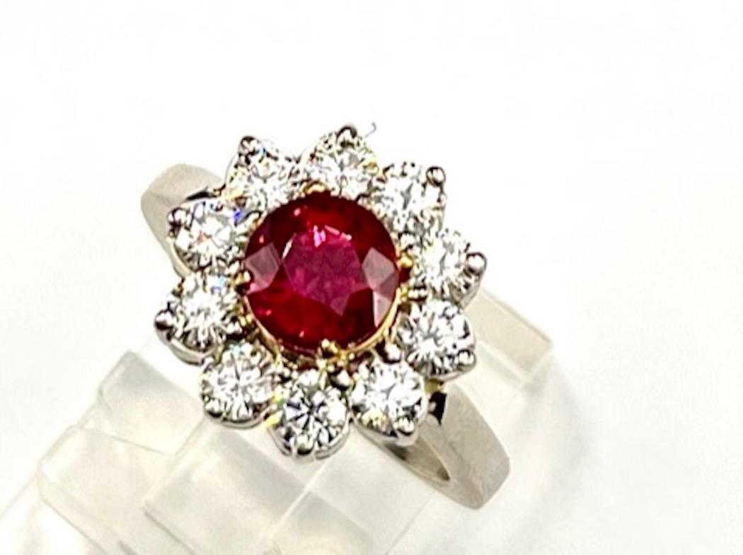 This classic, custom designed ring features a beautiful deep red Round Brilliant Ruby with a GIA Grading Report.  The ruby is surrounded by 10 large natural white diamonds that weigh 1.20Ct total weight.  The origin of this ruby, as indicated by the
