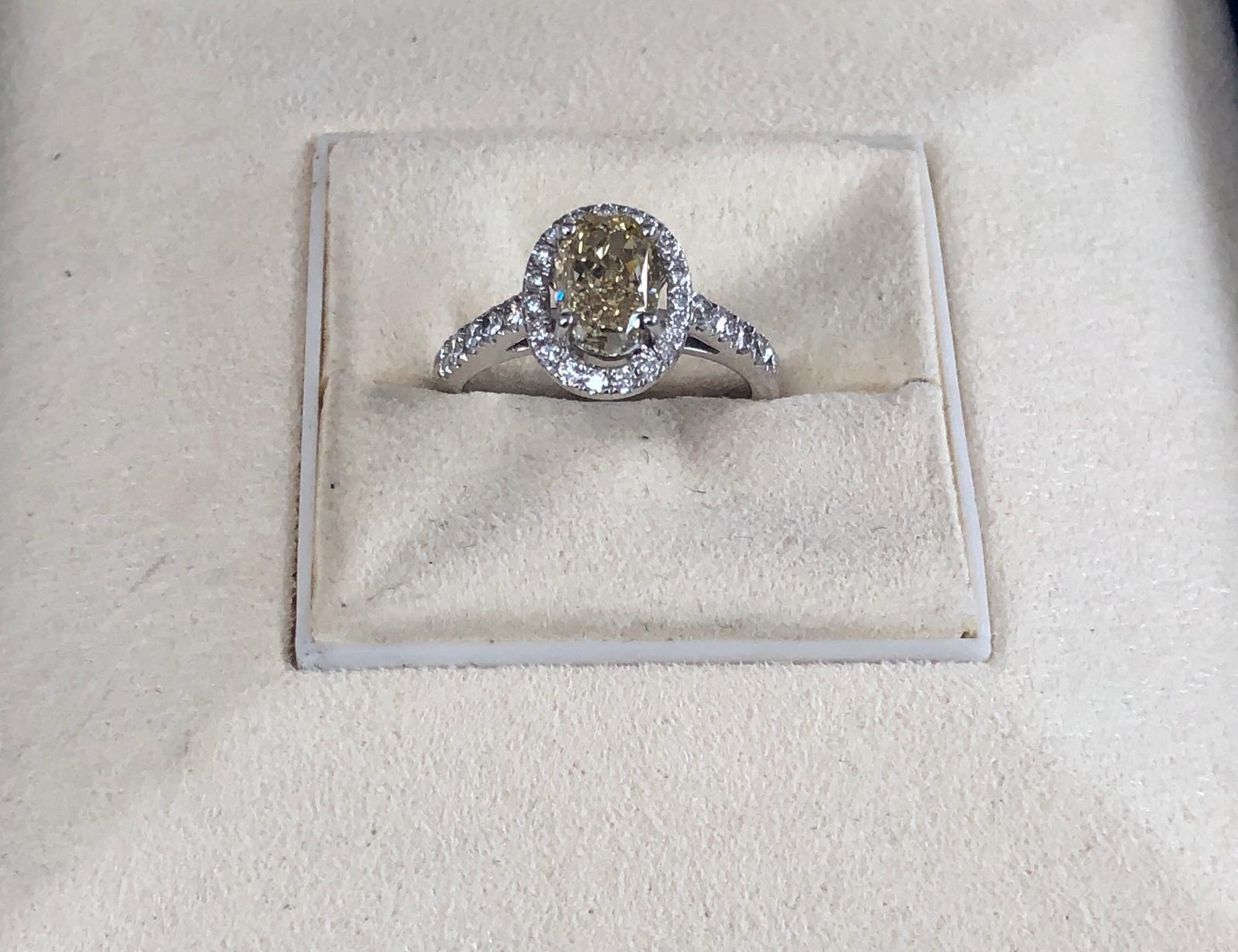 Fancy Brownish Yellow natural oval diamond weighing 1.75 carats by GIA.  Half way paved white diamonds in the halo setting. Its transparency and luster are excellent. set on 18K white gold, this ring is the ultimate gift for anniversaries,