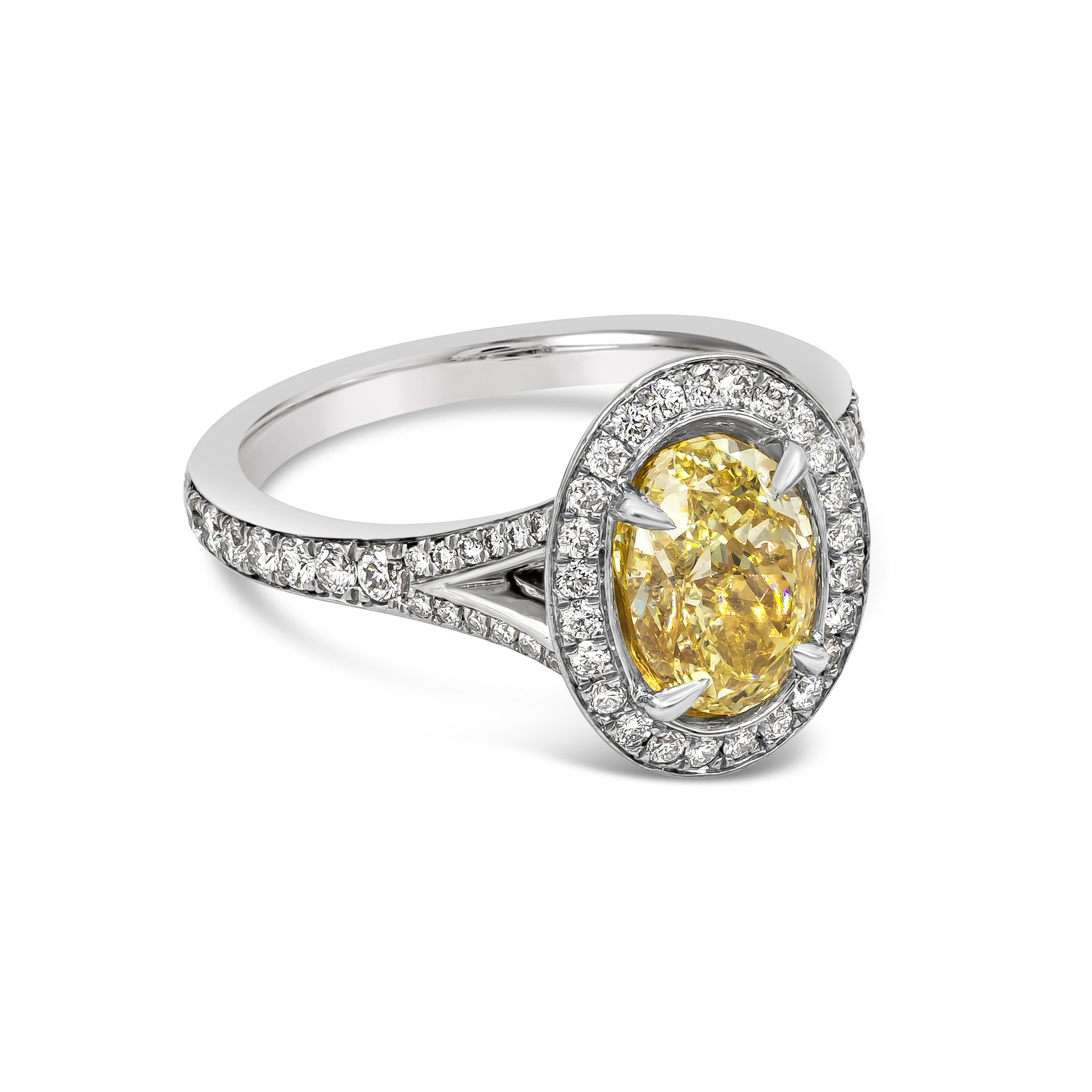 A gorgeous engagement ring, featuring a color-rich 1.76 carats oval cut diamond certified by GIA as Fancy Light Yellow color and VS2 clarity. Surrounded by a single row of round brilliant cut diamonds in a halo bezel setting. Set on a split-shank