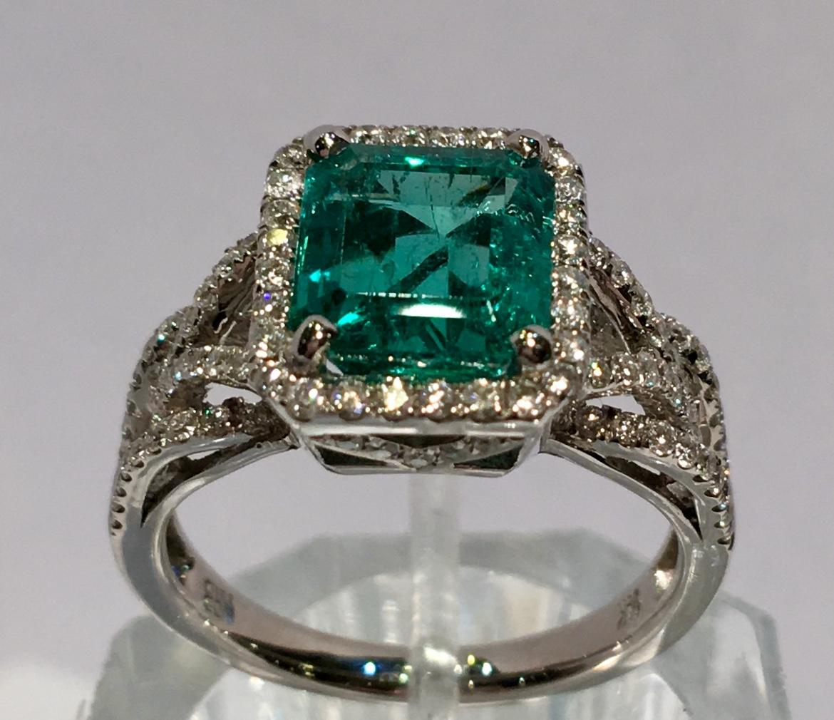 Octagonal, step cut, natural beryl, Columbian emerald is prong set in 14 karat white gold and enhanced by a rectangular halo of round brilliant diamonds and diamond micro-pave details on the shank and the basket.  Underside of basket features a