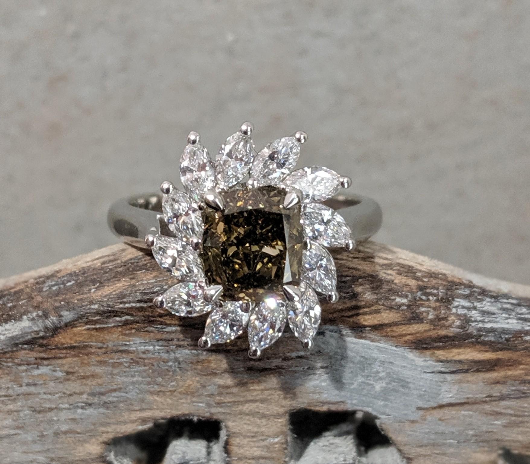 Anello da cocktail certificato GIA e realizzato in platino con (1) diamante Fancy marrone scuro-giallo verdastro tagliato a cuscino del peso di 1,80ct e circondato da (12) diamanti a forma di marquise del peso di 1,05cttw con un colore F e una