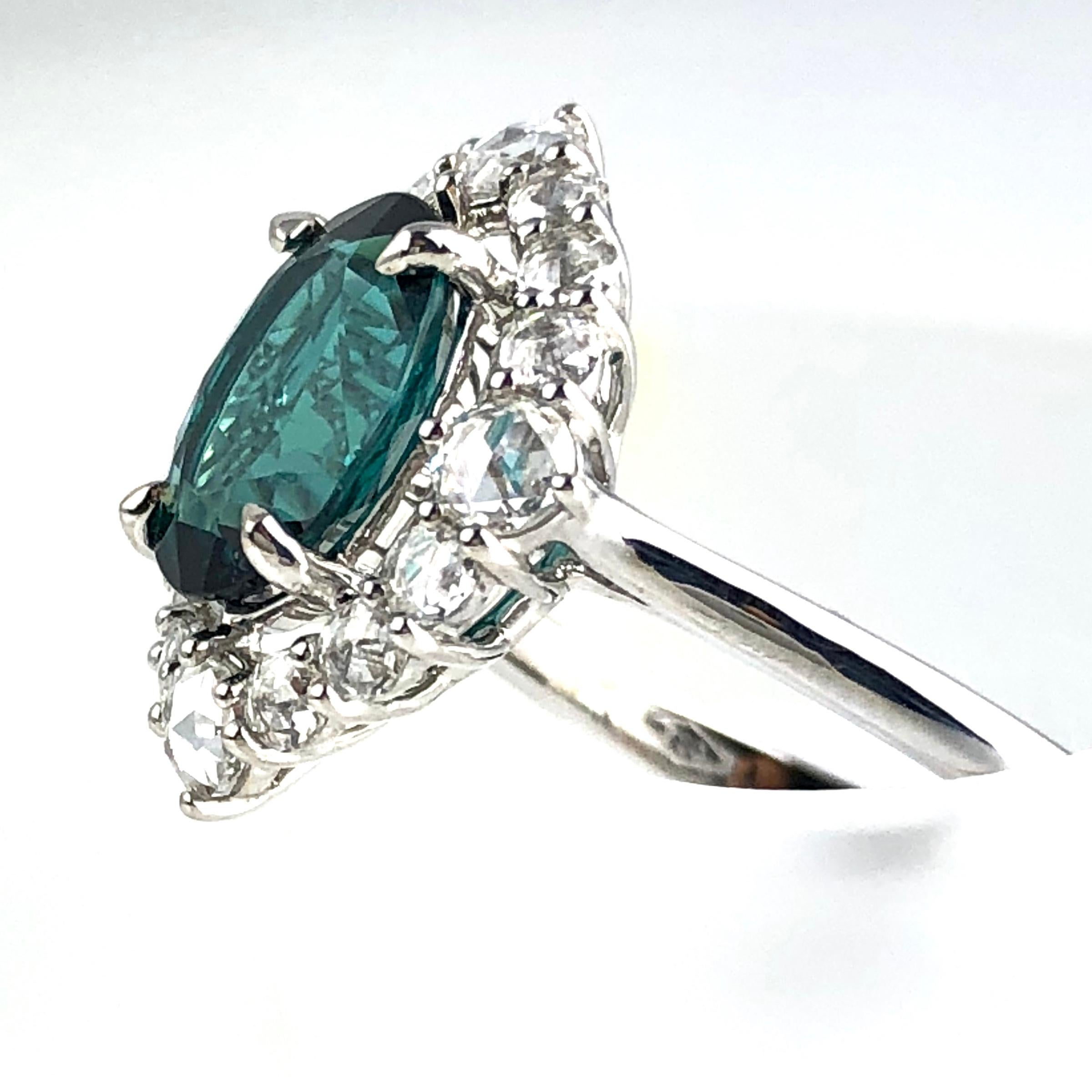 Eleganz trifft auf Extravaganz in diesem prächtigen Ring mit einem GIA-zertifizierten blaugrünen Turmalin von 1,81 Karat im Ovalschliff, der von 0,62 Karat schillernden weißen Diamanten umringt ist. Aus jedem Blickwinkel verströmt dieser Ring eine