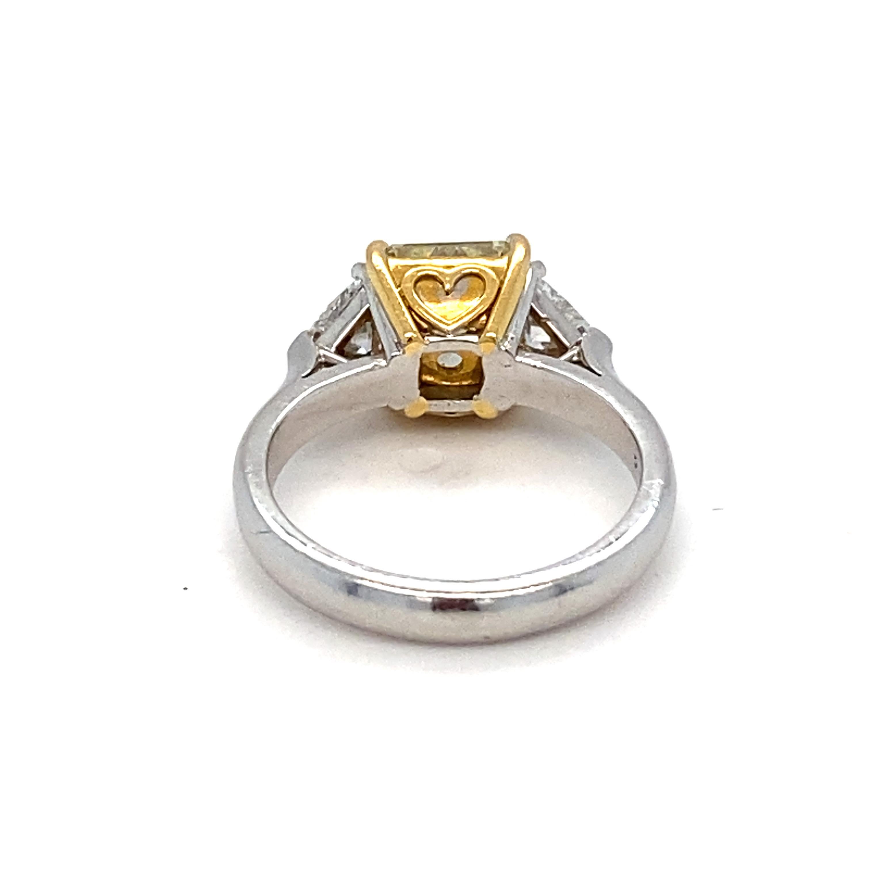 Gia Certified 1.83 Carat Natural Fancy Light Yellow Cushion Diamond is showcased in the center with two trillion white diamonds on the sides. Center stone is mounted in 22K yellow gold and the ring is in platinum. This ring is a timeless elegant