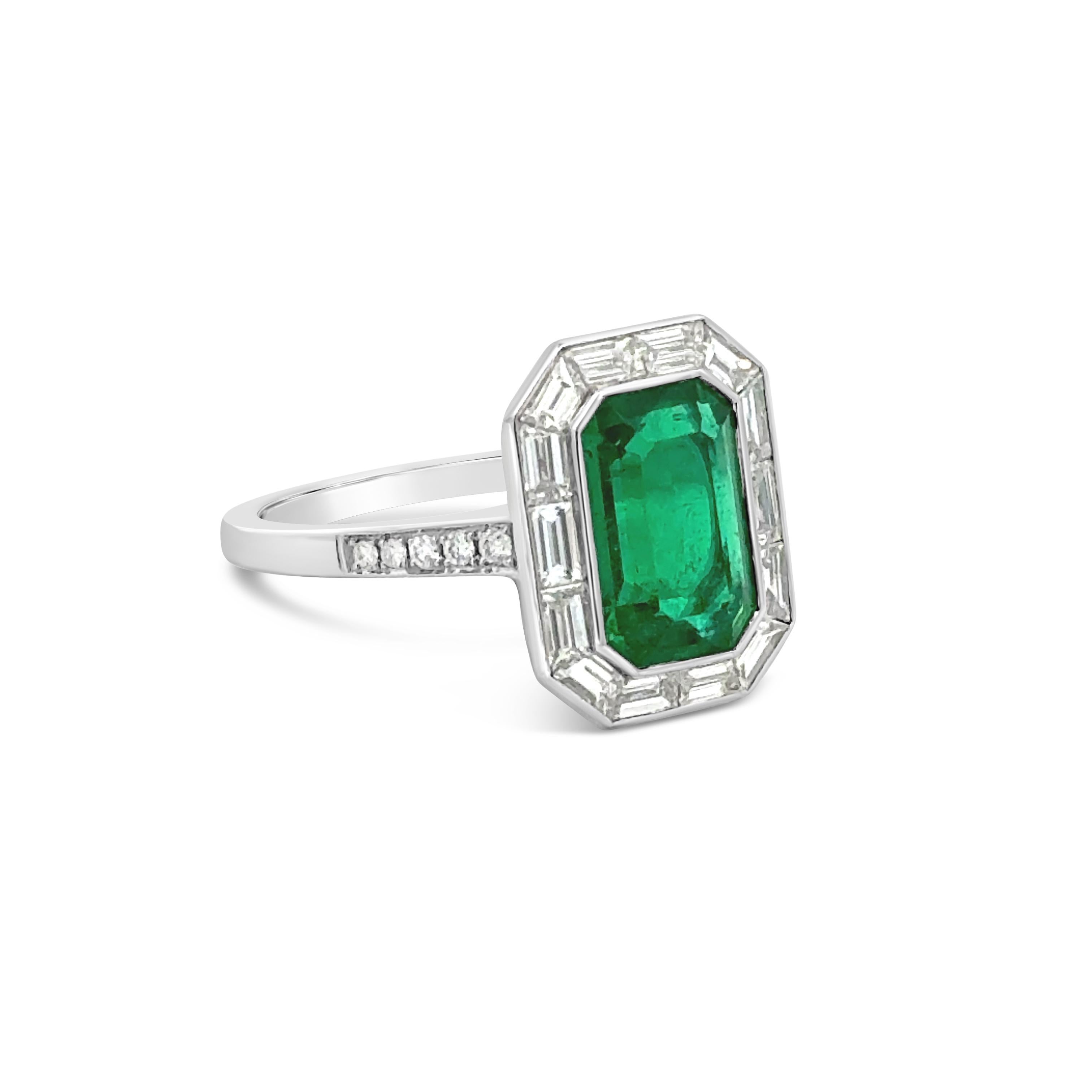 A stunning engagement ring, featuring a 1.86 carats emerald cut green emerald, bezel-set in a platinum mounting. Surrounded by a halo of channel-set tapered baguette cut diamonds and accented by a diamond encrusted shank in a half-eternity setting.